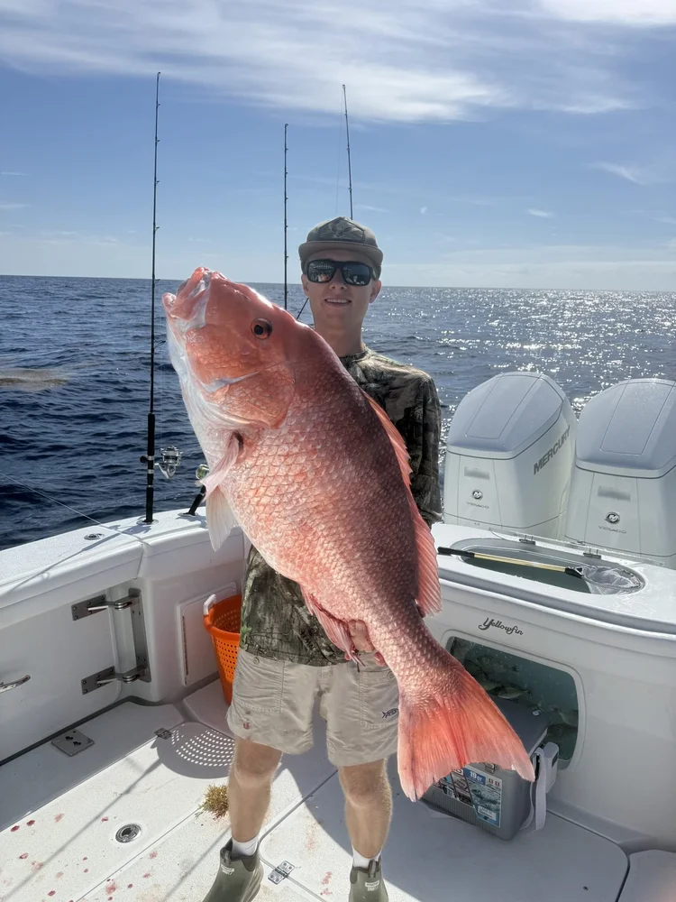 An angler holding a big catch aboard the 42' Yellowfin