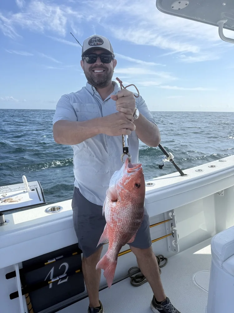 An angler with his catch under a blue sky on the 42' Yellowfin