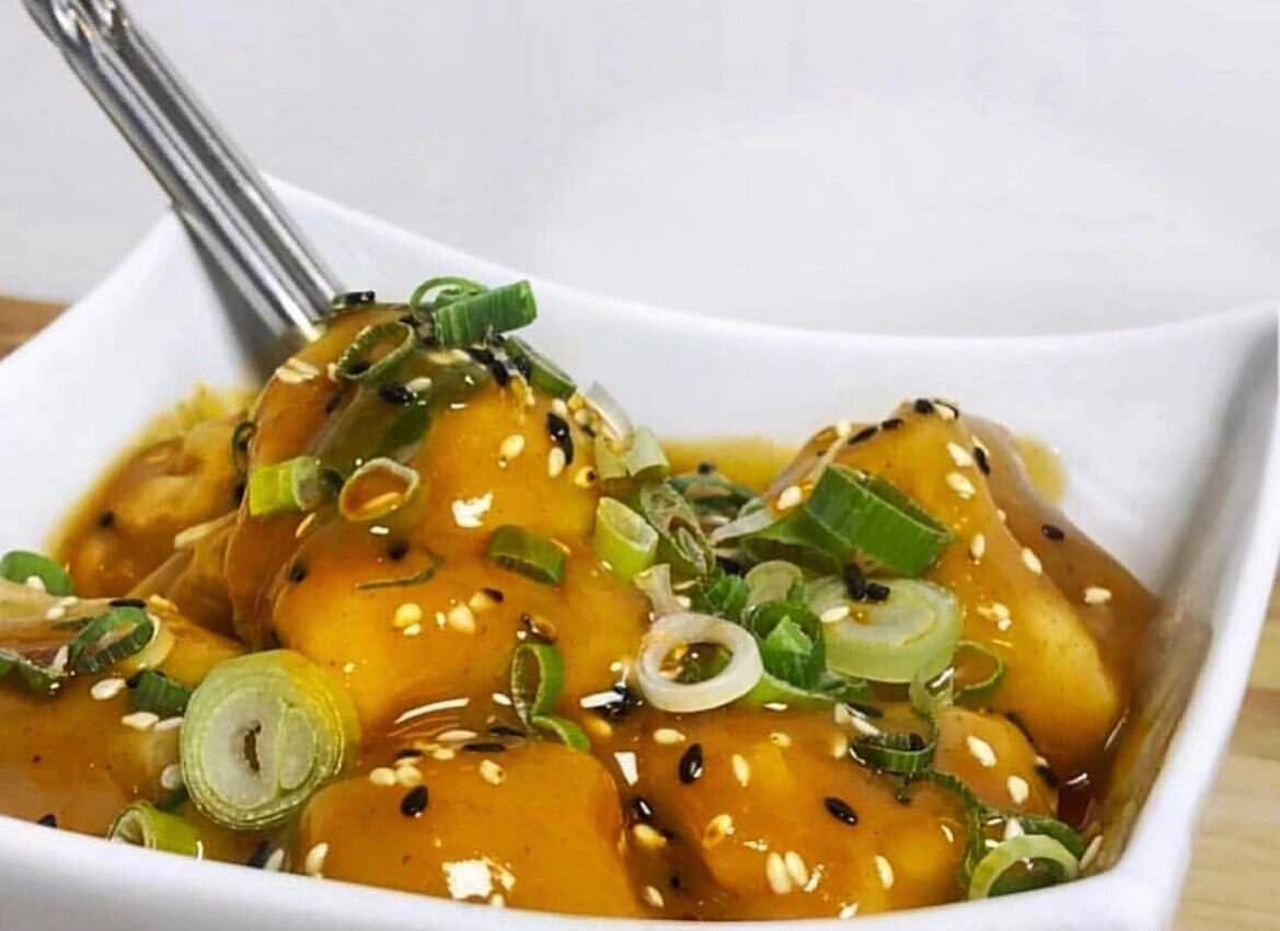 Silky, tender dumplings draped in our signature peanut butter sauce, topped with sesame seeds and diced chives.