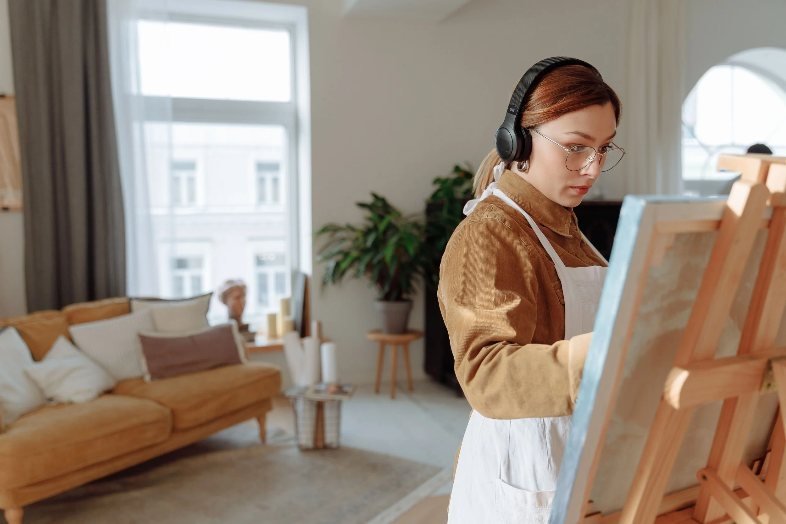 Woman wearing headphones while deeply focused on painting