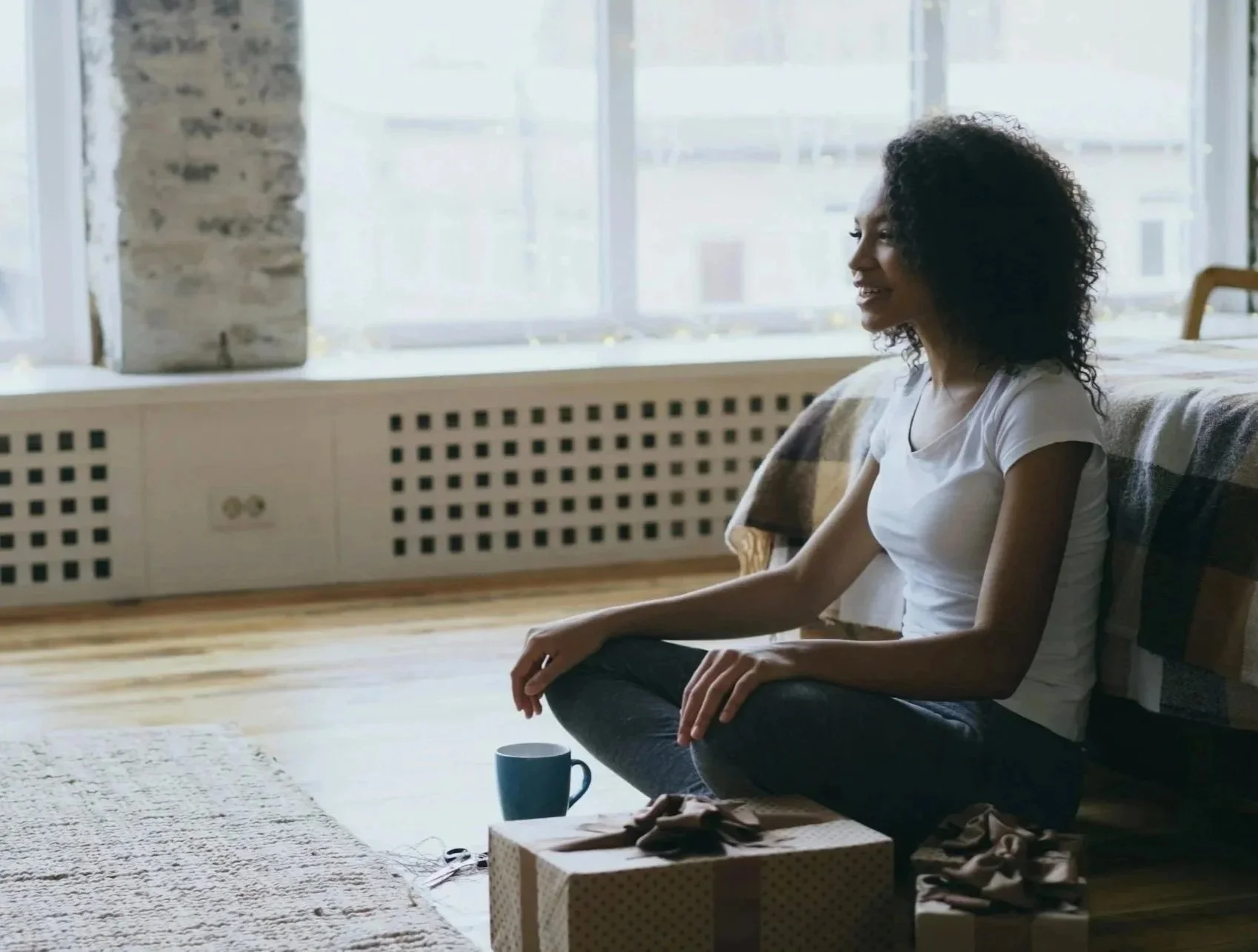 Woman sitting on floor in front of her bed