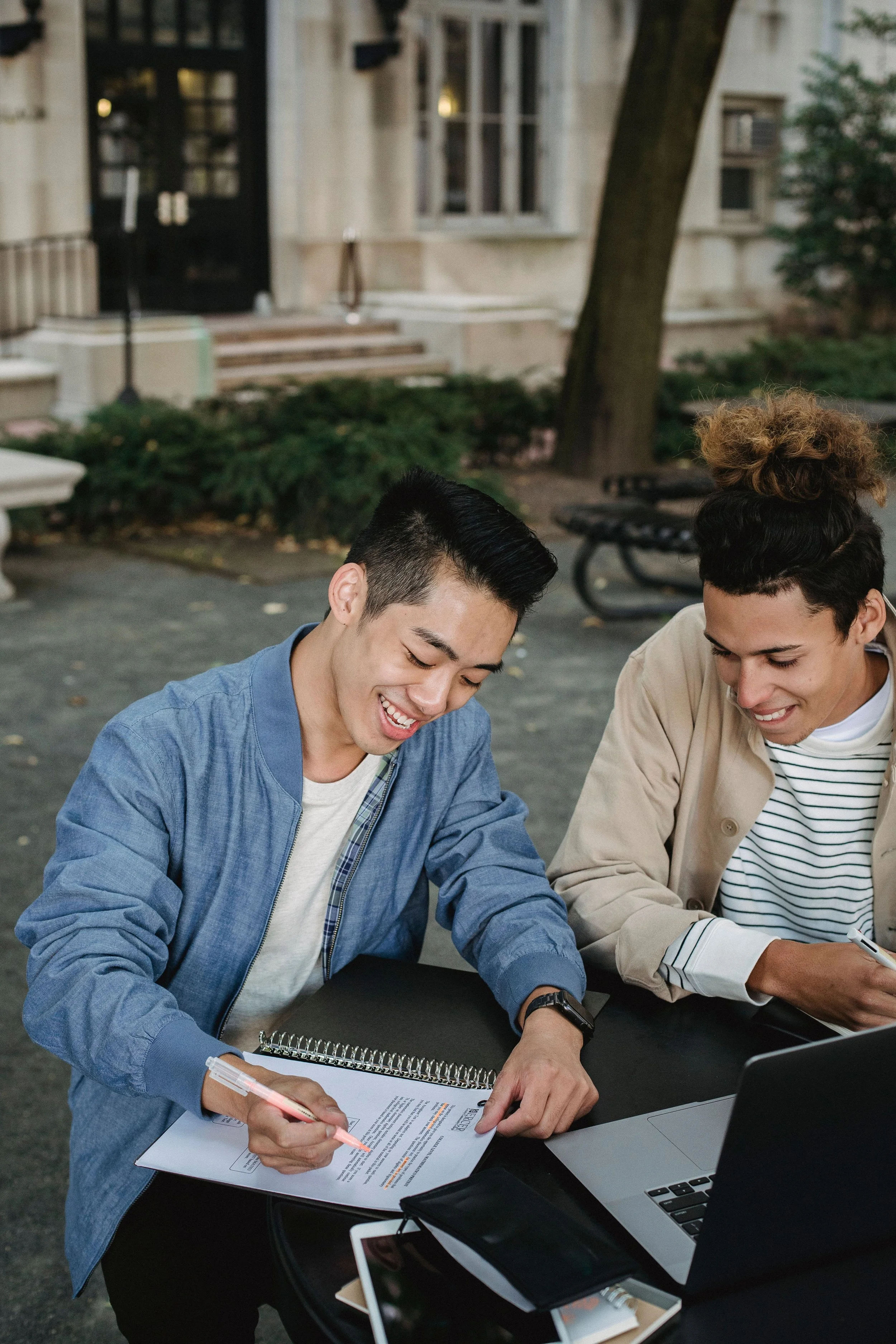 Two men sitting at an outside table highlighting a document