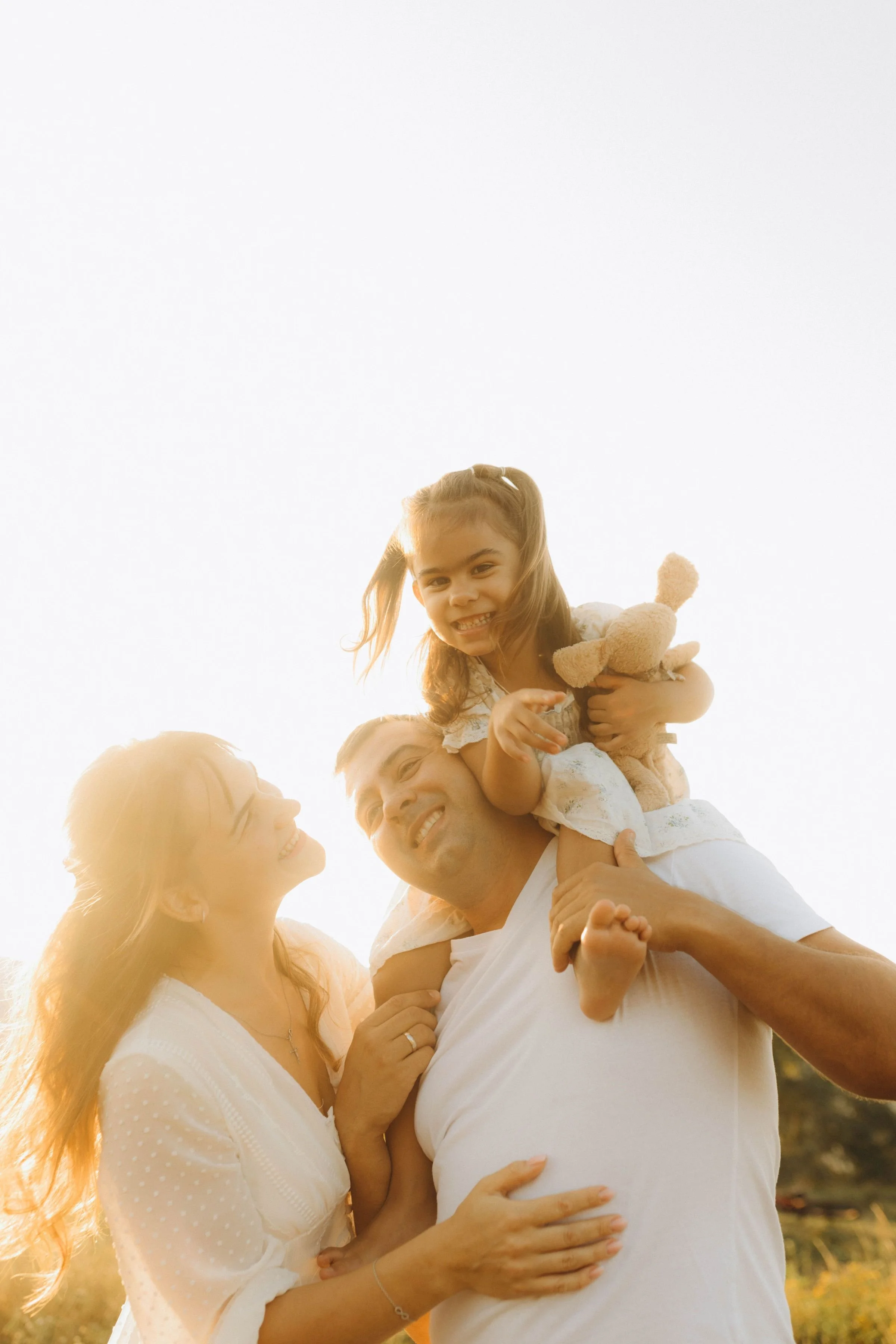 Young girl on dads shoulders with mom looking up at her
