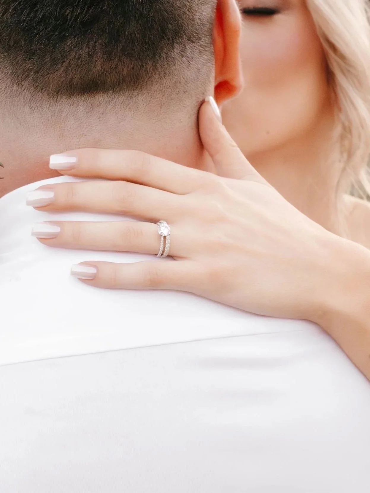 Close-up of a woman kissing a man, showing her hand with an engagement ring on her finger.
Makeup by Georgia Lipscombe at Georgia Peach Beauty. Credit to Kaile Thorne Photography