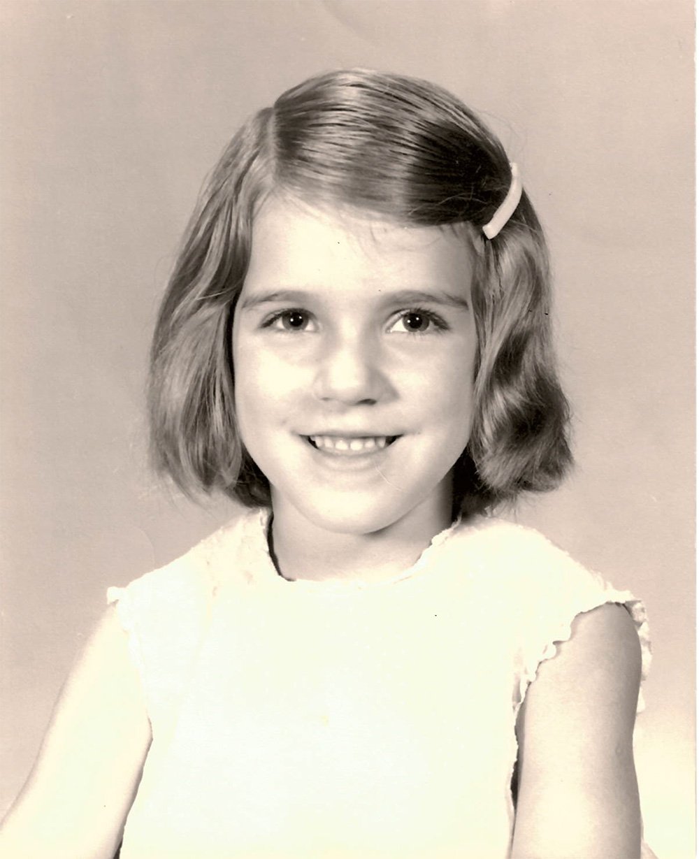 Young Julia Brim-Edwards with shoulder-length hair, a hair clip on the side, and a smiling expression.