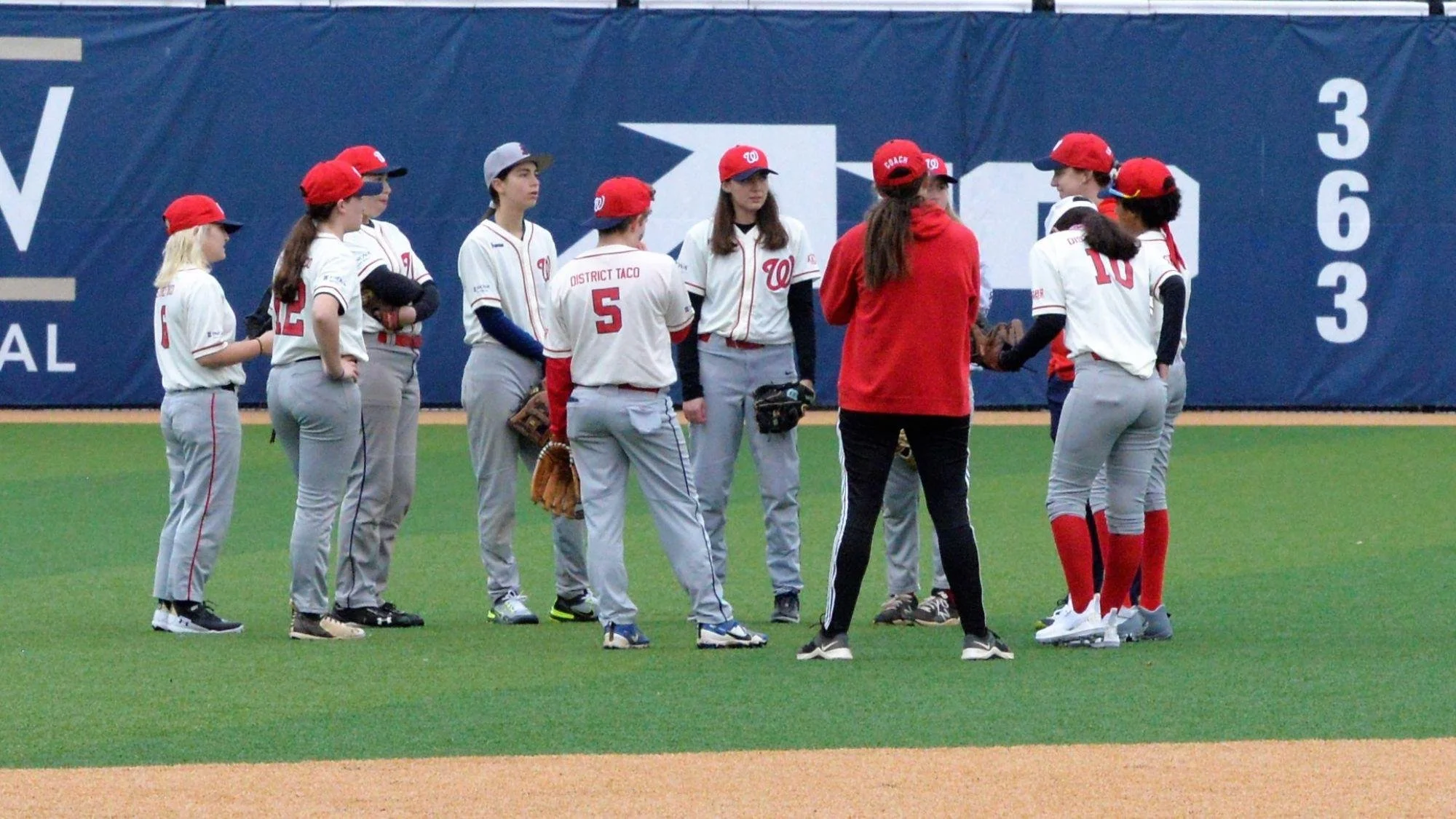 DC Girls Baseball High School Players and Coach Hammond on the field.