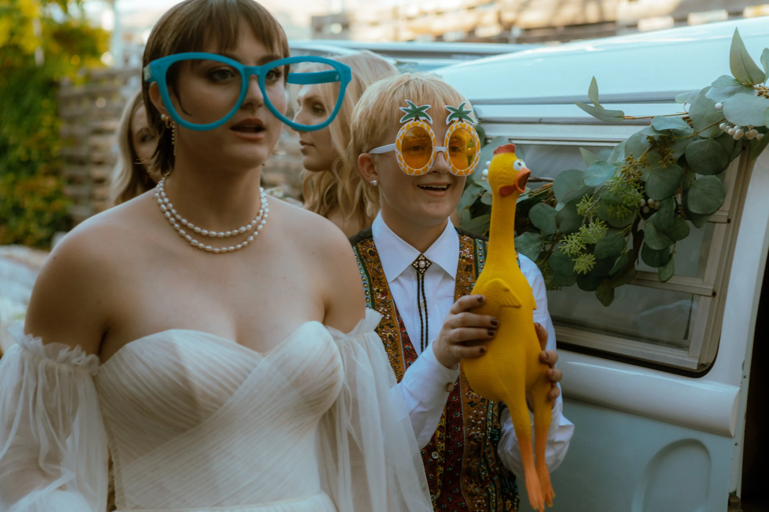a couple pose with silly props outside a photo booth