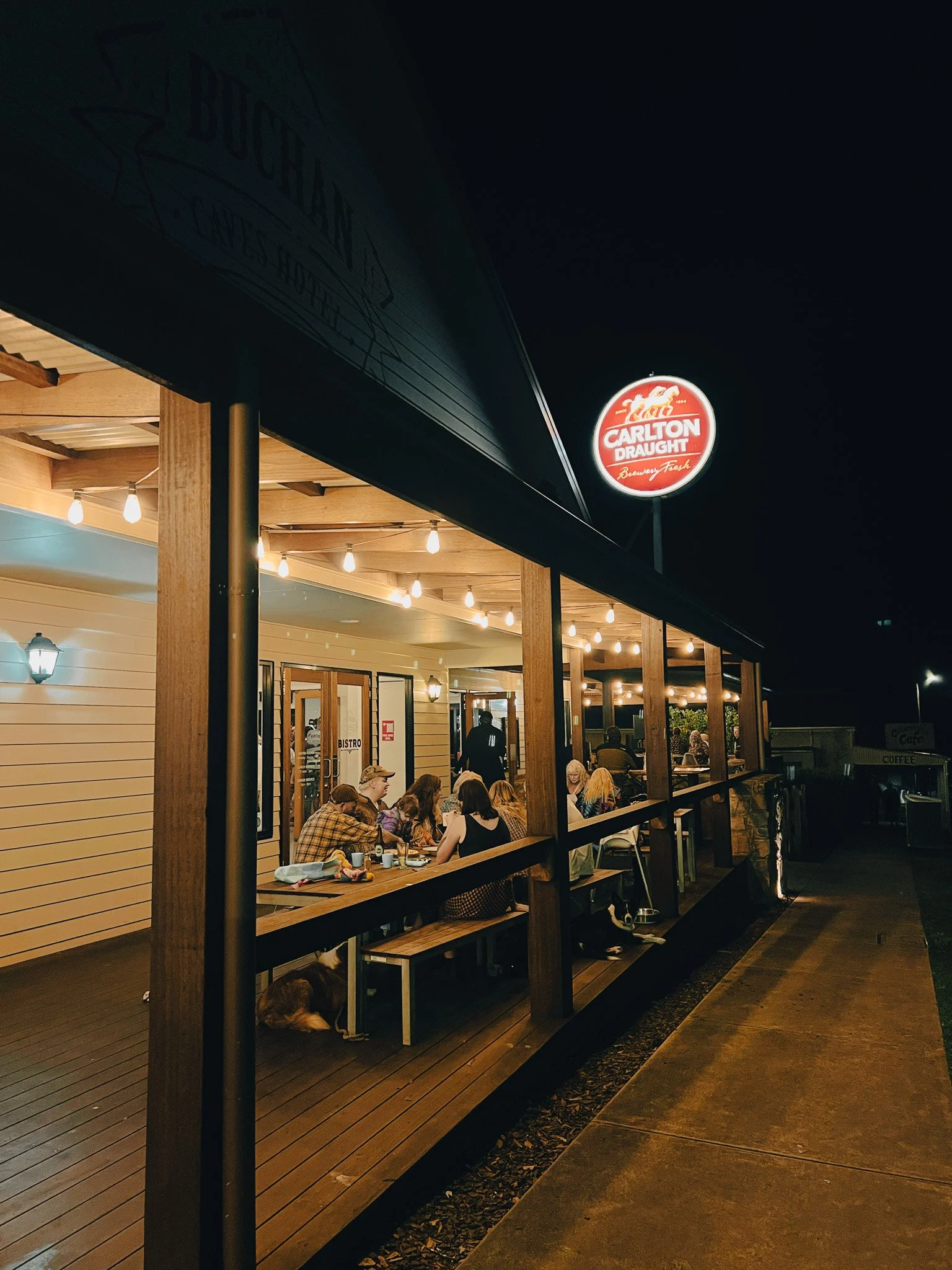 Night view of Buchan Pub with people sitting at tables under string lights.