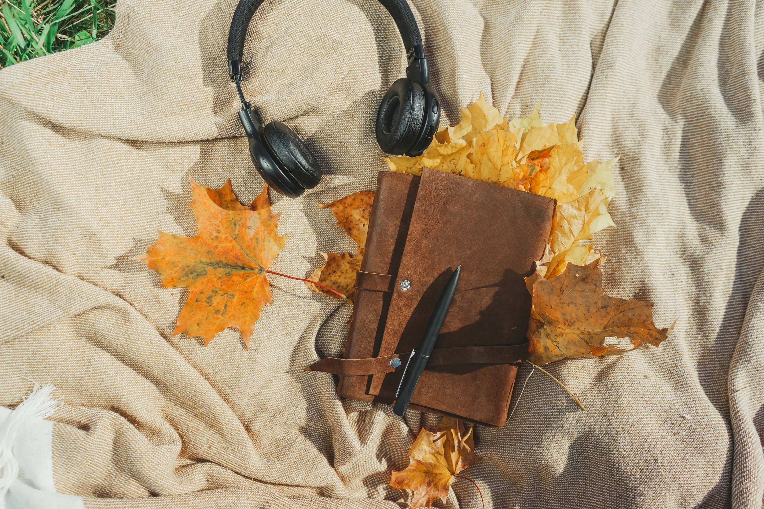 An image of headphones and a journal on a blanket that Multidimensional Money is using to link to the video and audio lessons included as part of the Prosperity Redefined membership package.