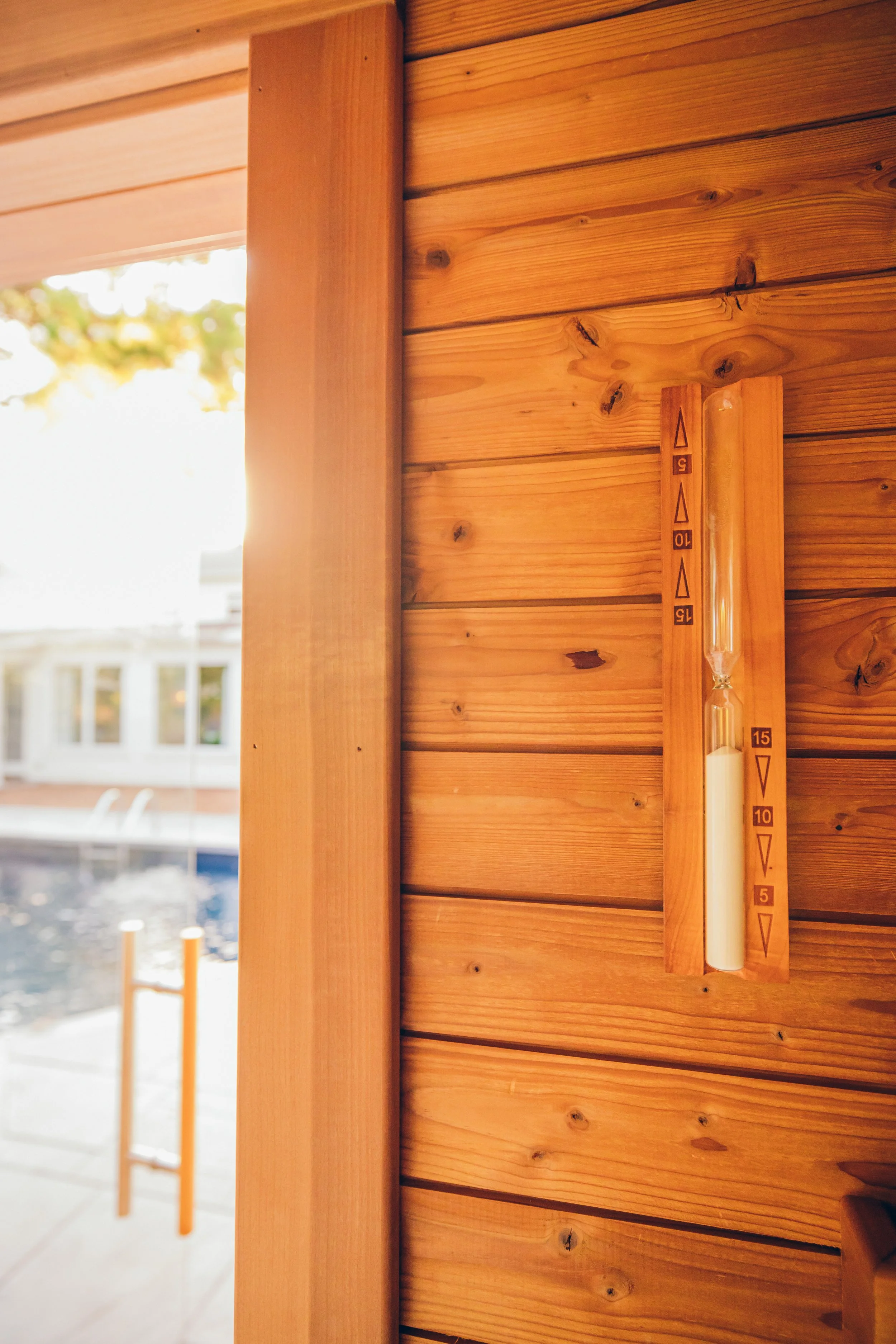 Chillfire Sauna Company wooden sauna wall with a mounted sand timer showing approximately 10 minutes remaining, designed for home wellness and relaxation.
