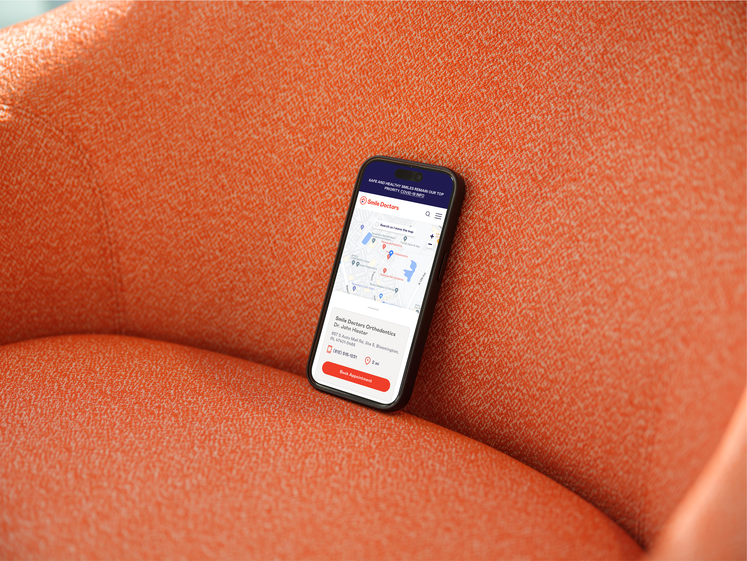 iPhone 15 Pro mockup on an orange fabric chair (Mockuuups Studio) (1).png