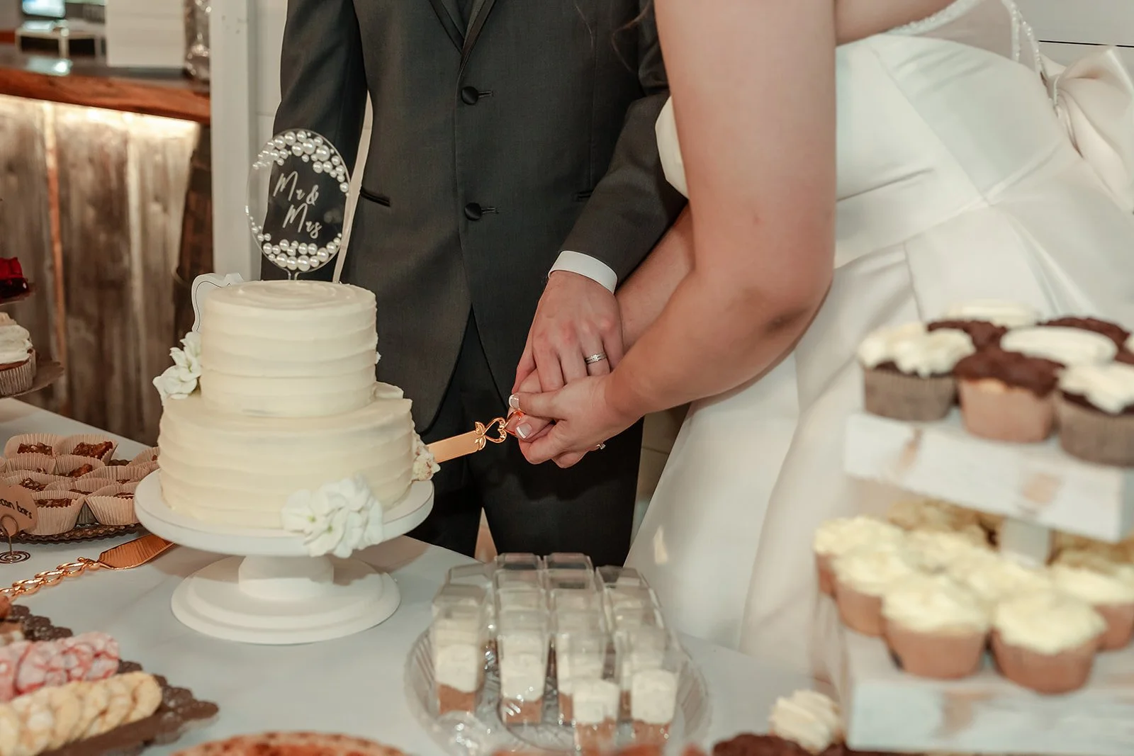 A bride and groom cutting a wedding cake together at their wedding reception.