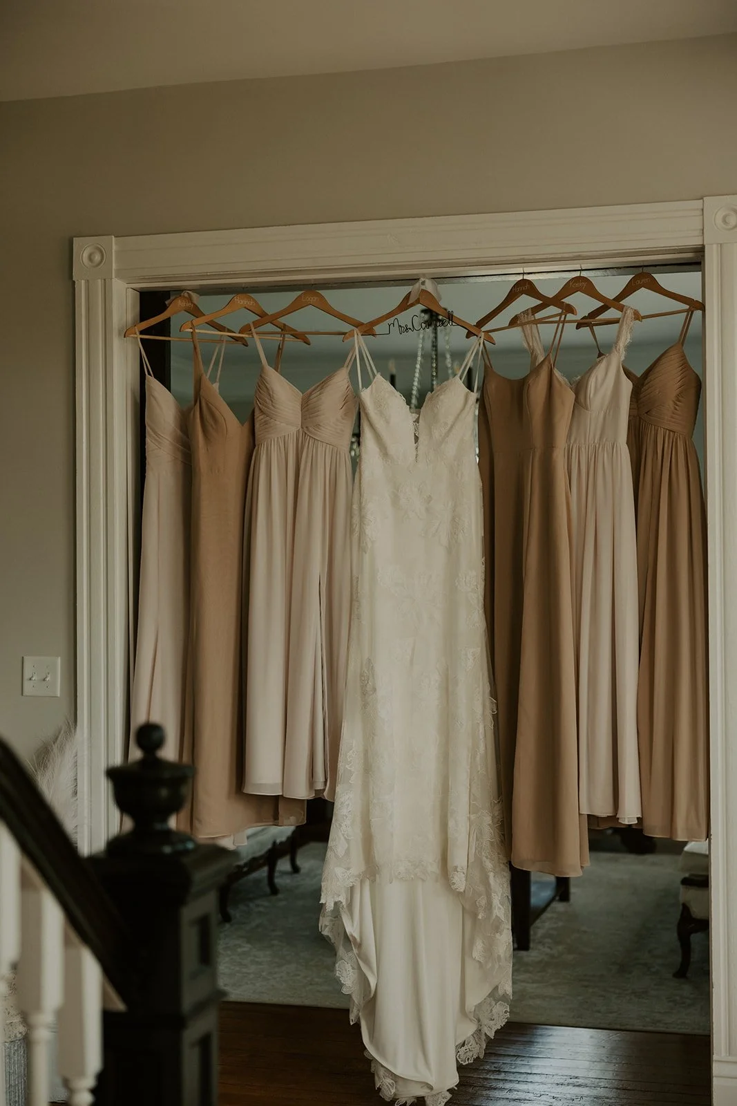 A wedding dress hangs in the center with seven other dresses surrounding it on a closet door.