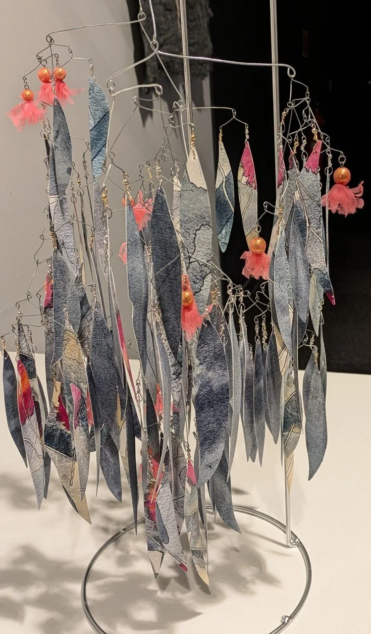 Colorful earrings hanging on a metal display stand.