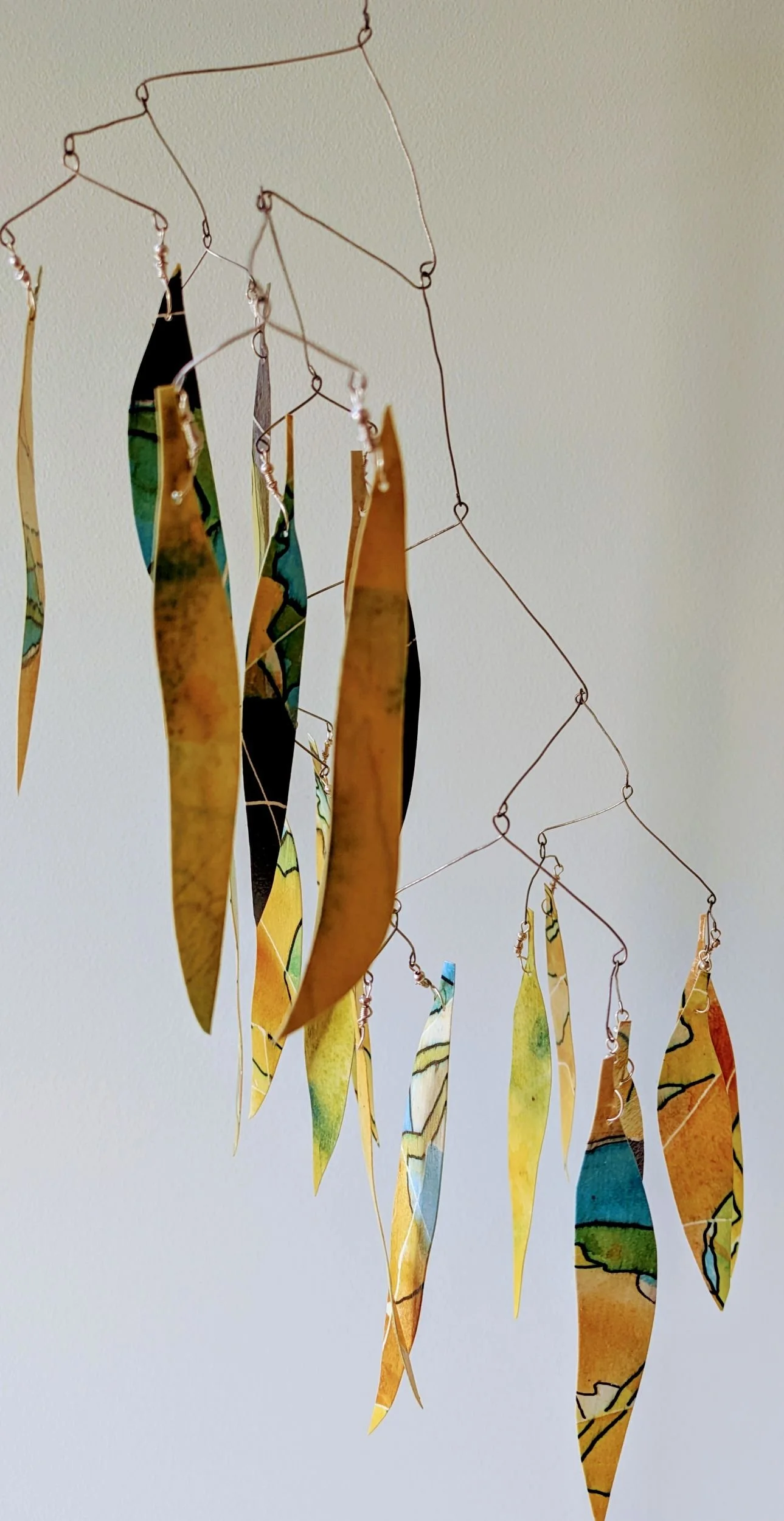 Hanging kinetic sculpture representing the leaves of an ironbark tree, made from yellow painted and sealed watercolour paper and wire frame.