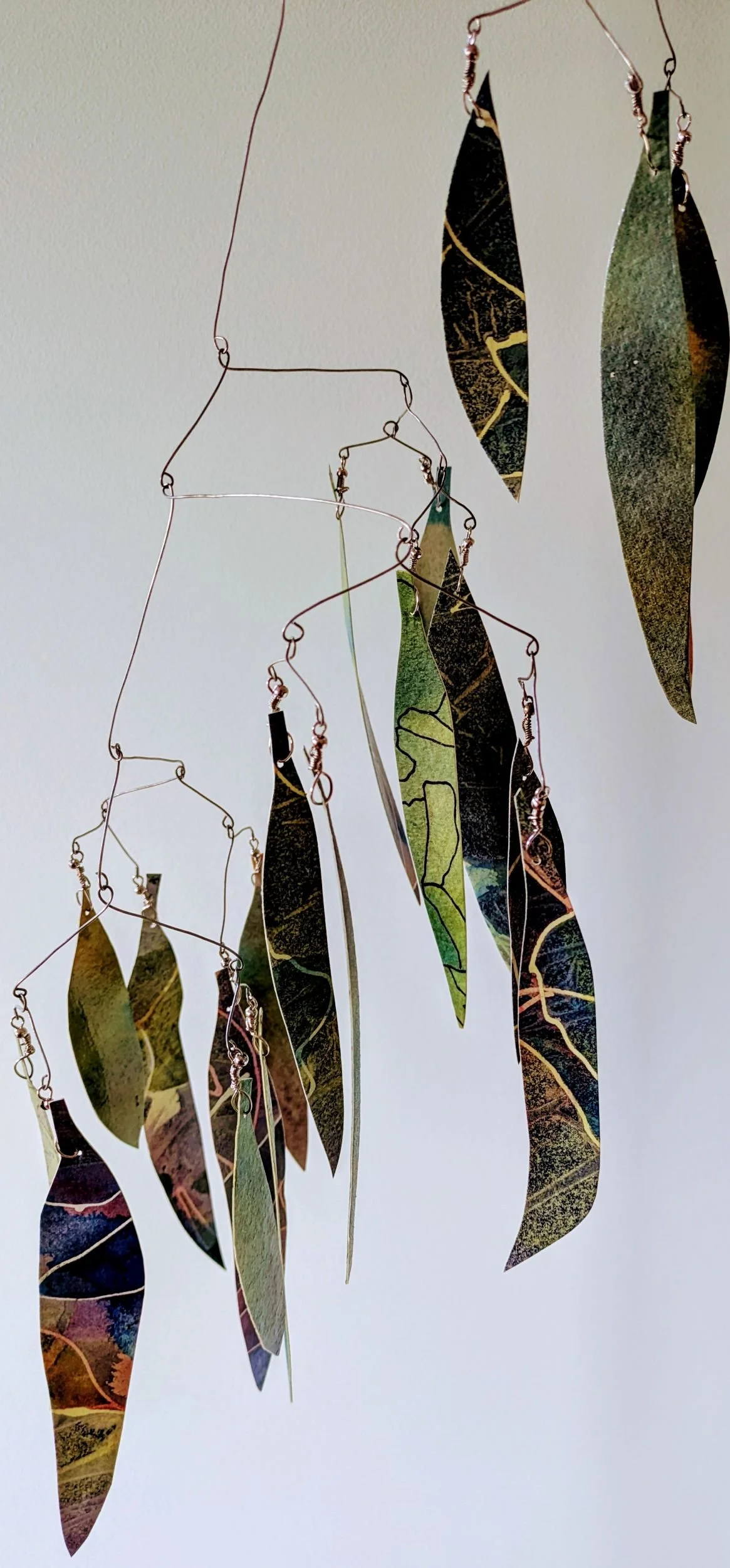 Hanging kinetic sculpture representing the leaves of an ironbark tree, made from green painted and sealed watercolour paper and wire frame.