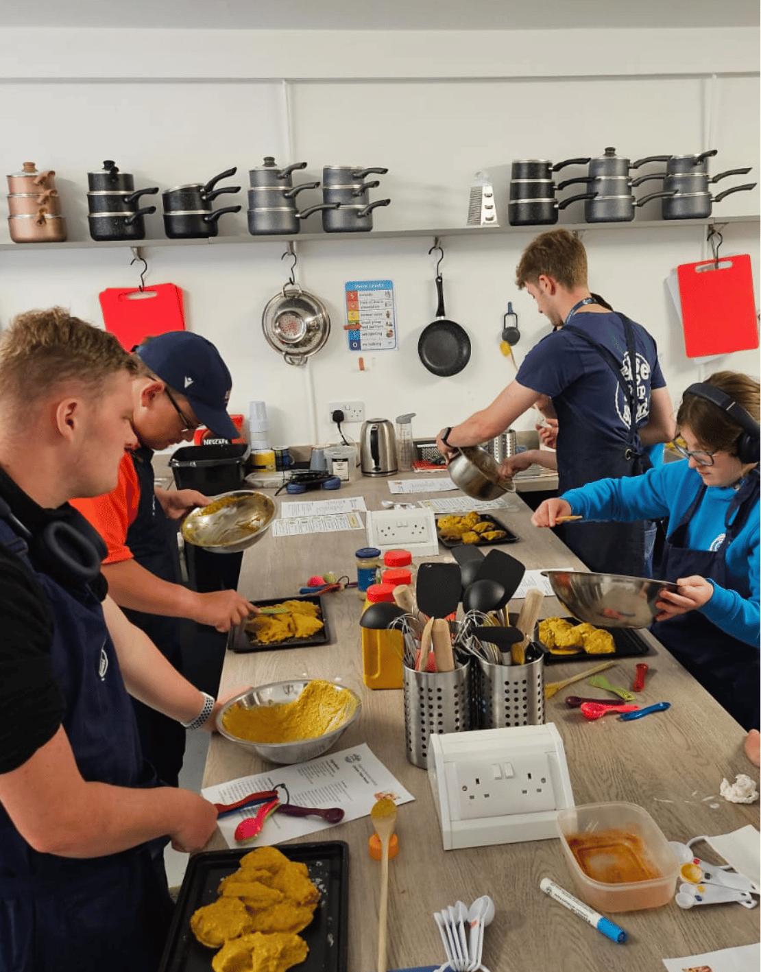 People preparing and serving food in a kitchen classroom