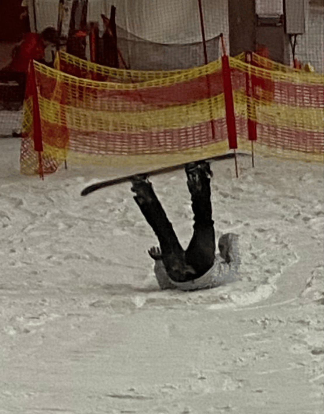 A snowboarder lying on their back after falling at an indoor ski centre