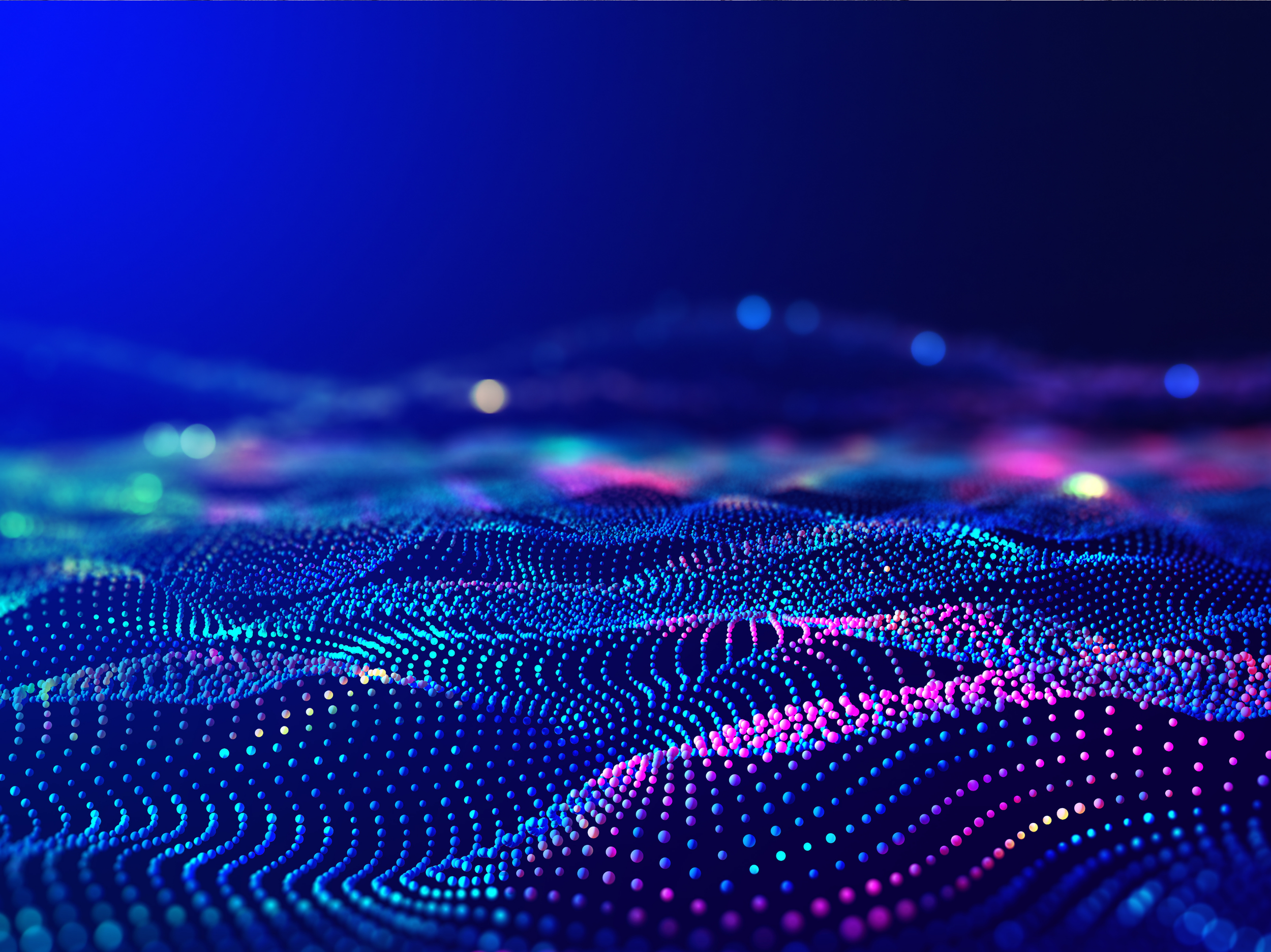 Abstract digital landscape of flowing waves made up of glowing dots in blue, purple and pink tones, suggesting data, sound or technological networks against a dark background.
