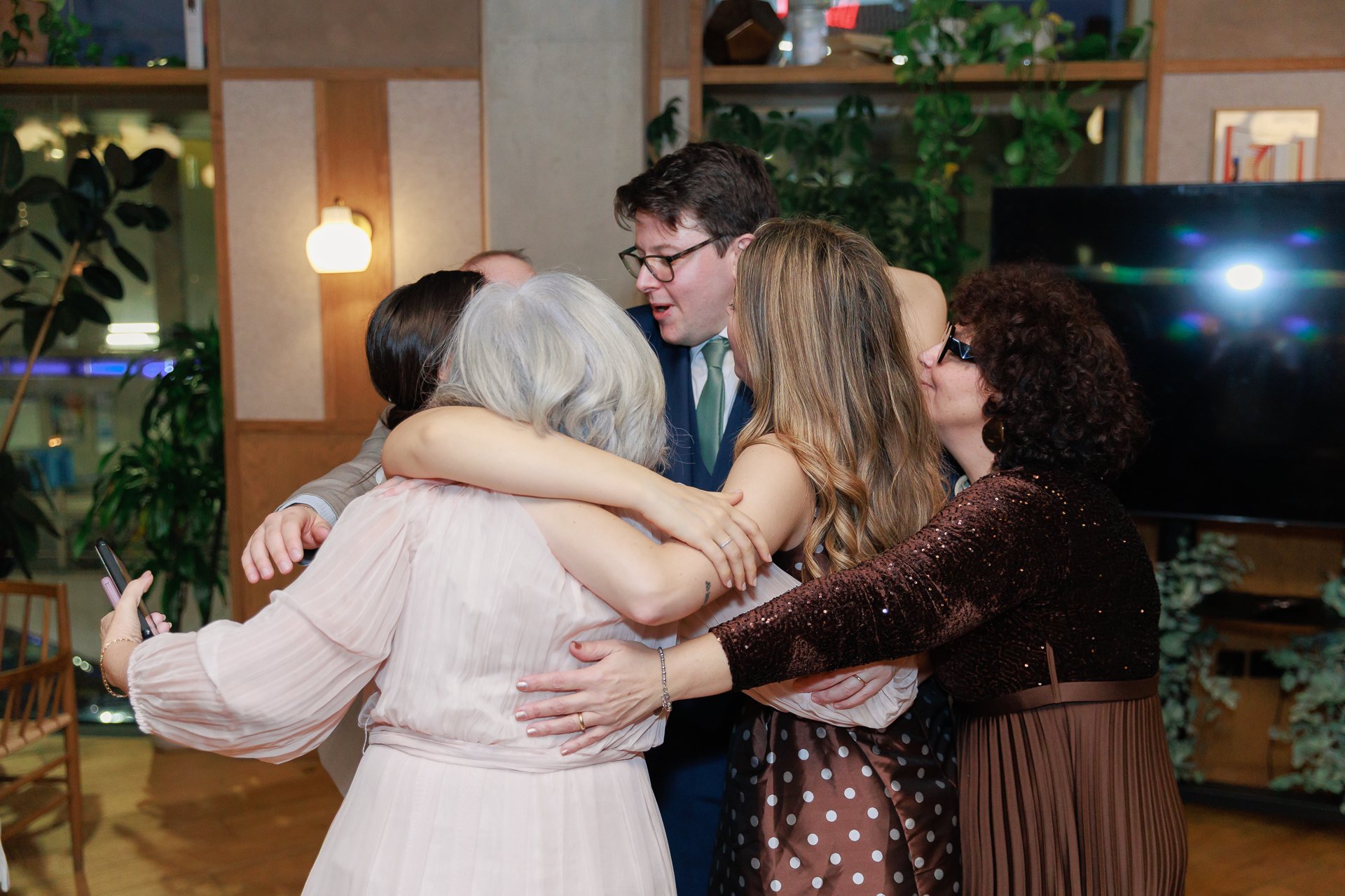 Group of six people hugging each other at a celebration or gathering
