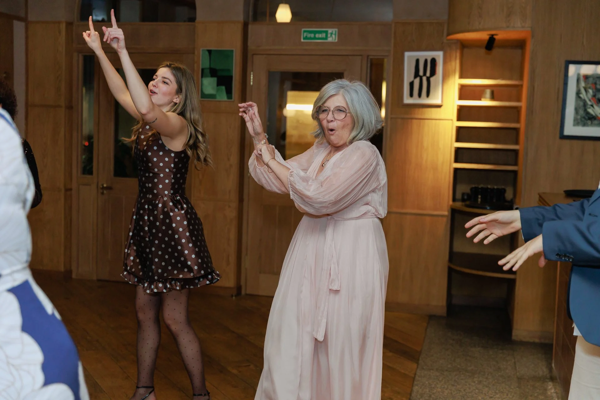People dancing and having fun at a party or celebration in a wooden-furnished room.