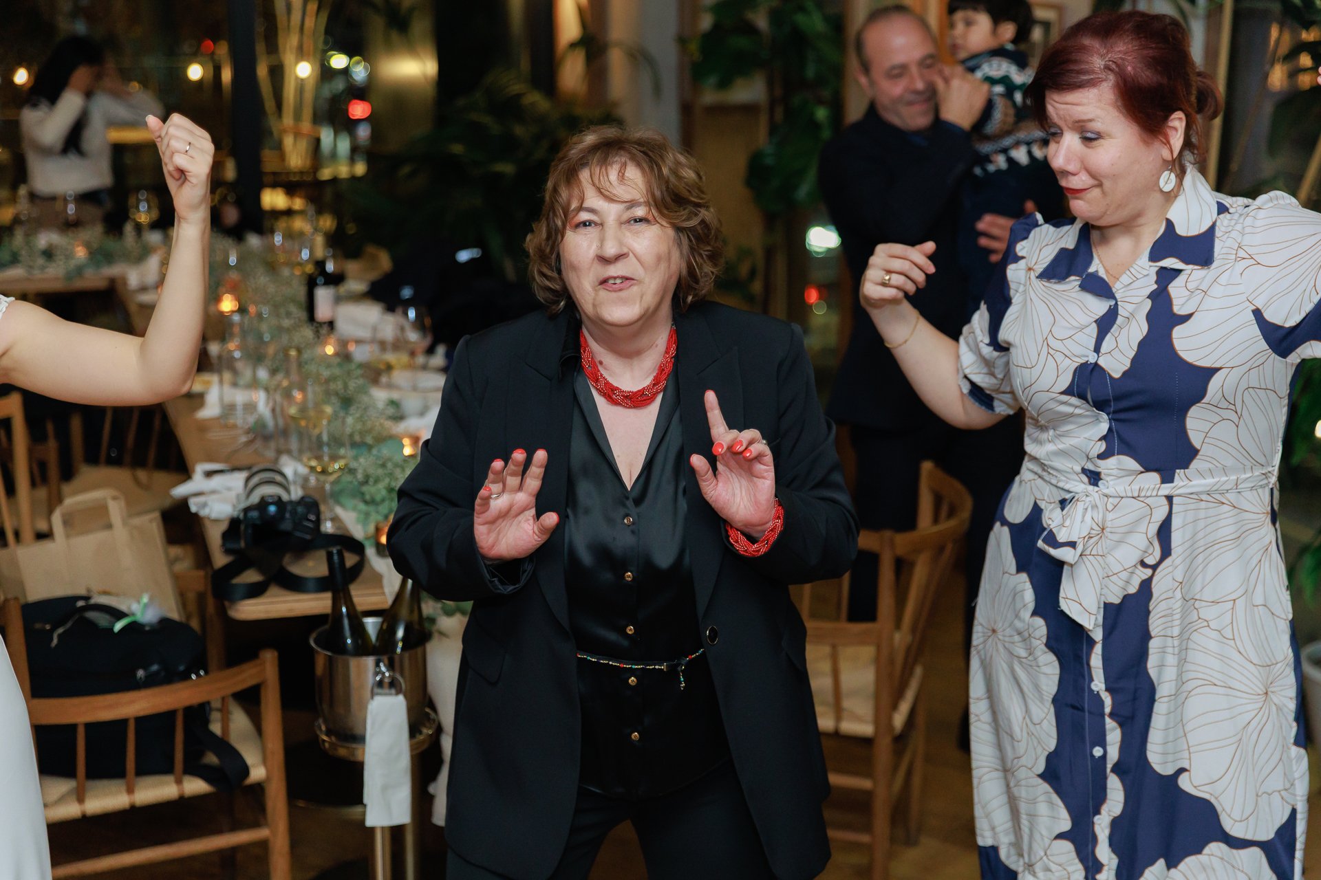 Group of people dancing and having fun at a social gathering or celebration in a restaurant or banquet hall.