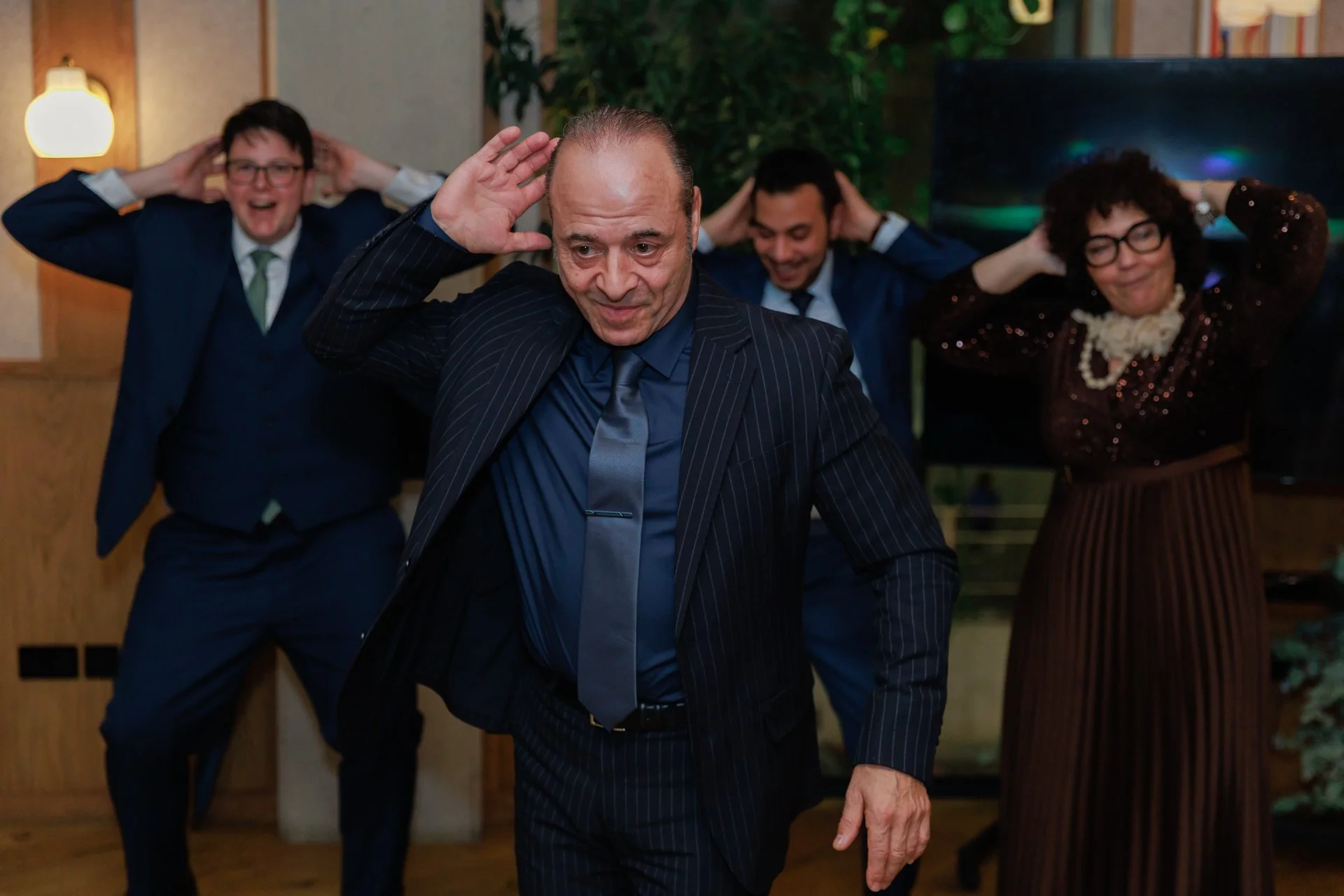 People dancing and celebrating at a party, dressed in formal attire.