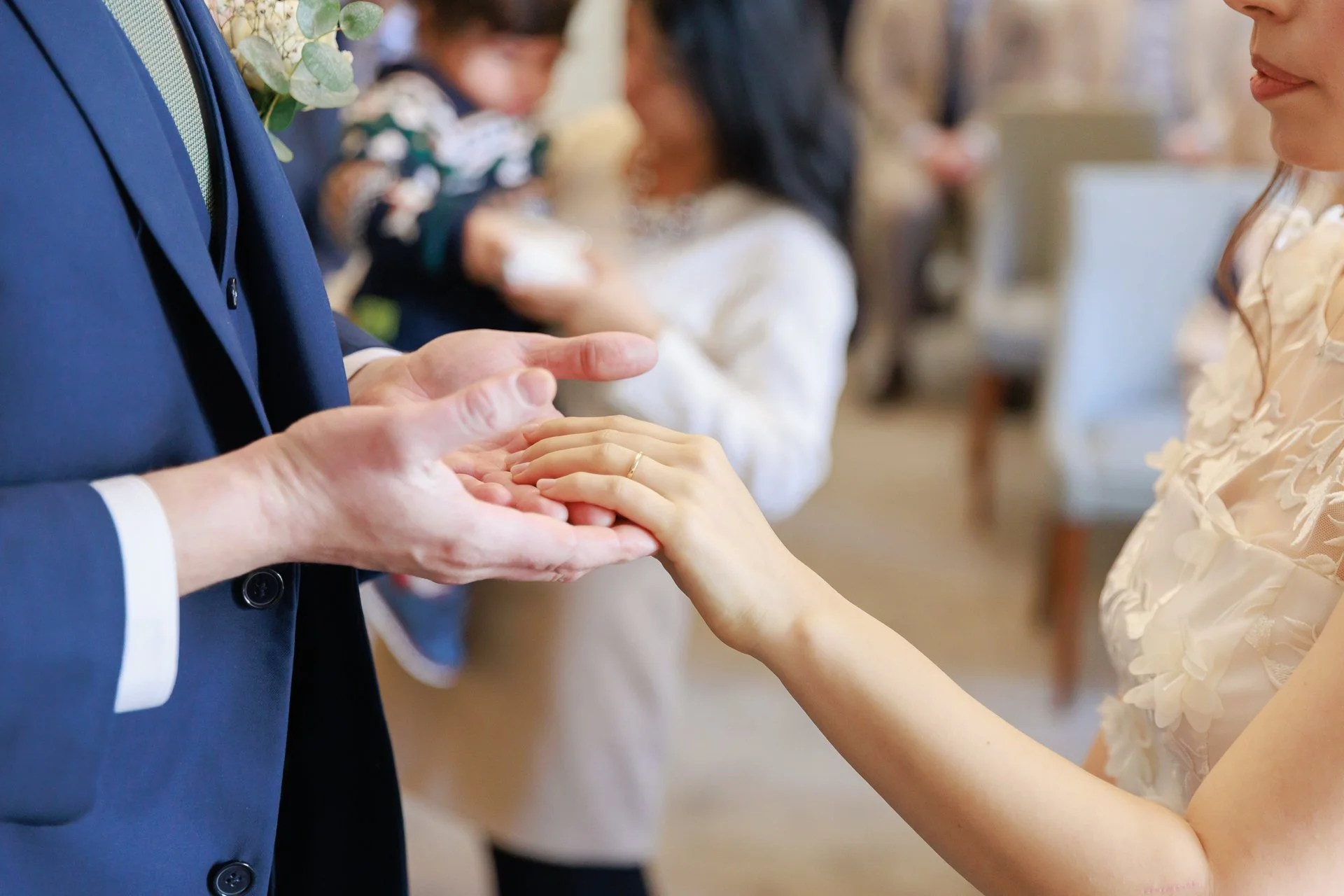 A wedding ceremony with a couple exchanging rings, focusing on the bride's hand placing a ring on the groom's finger.
