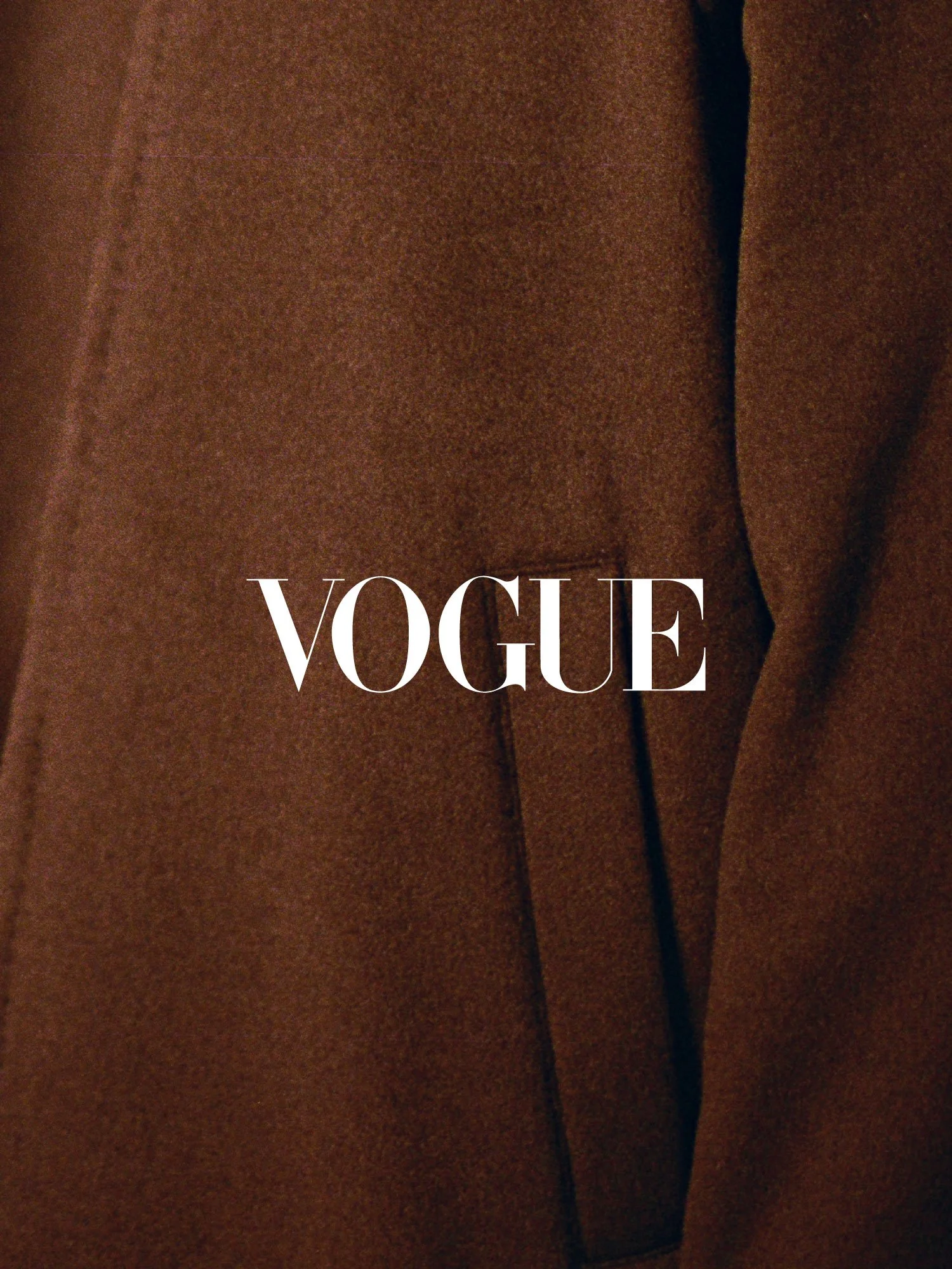 Close-up of a brown coat with the white 'VOGUE' logo overlayed in the center.
