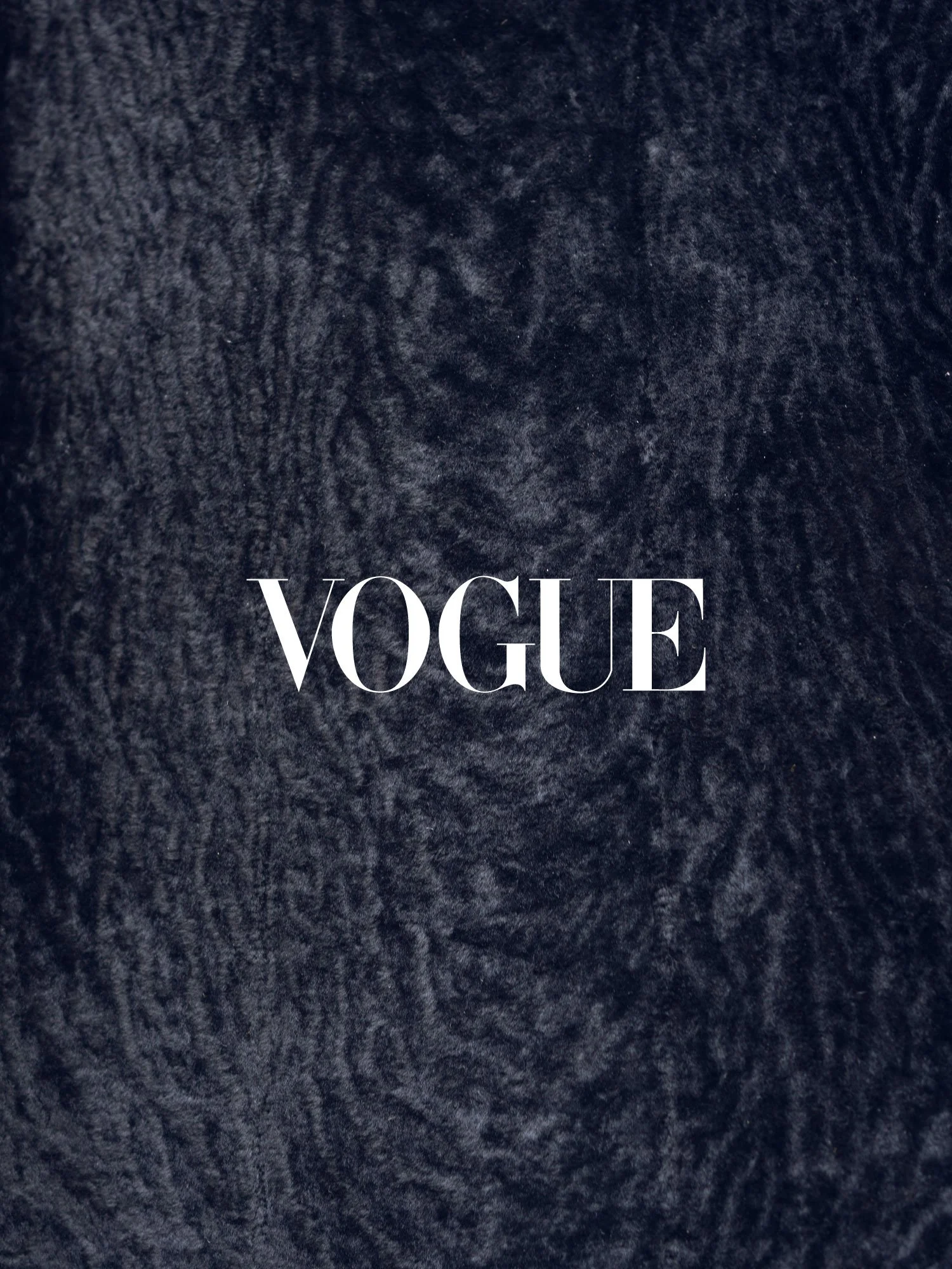 Close-up of a dark textured surface with the word "VOGUE" in white, centered in the image.