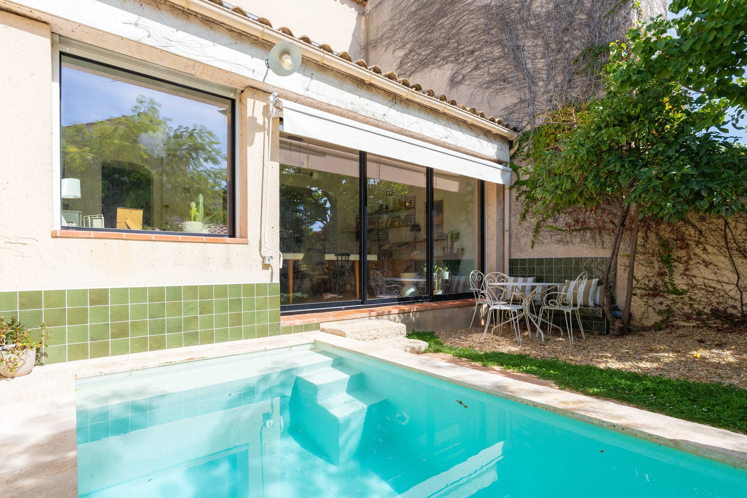 Vue du bassin et de la terrasse en travertin depuis le jardin vers la maison de ville.