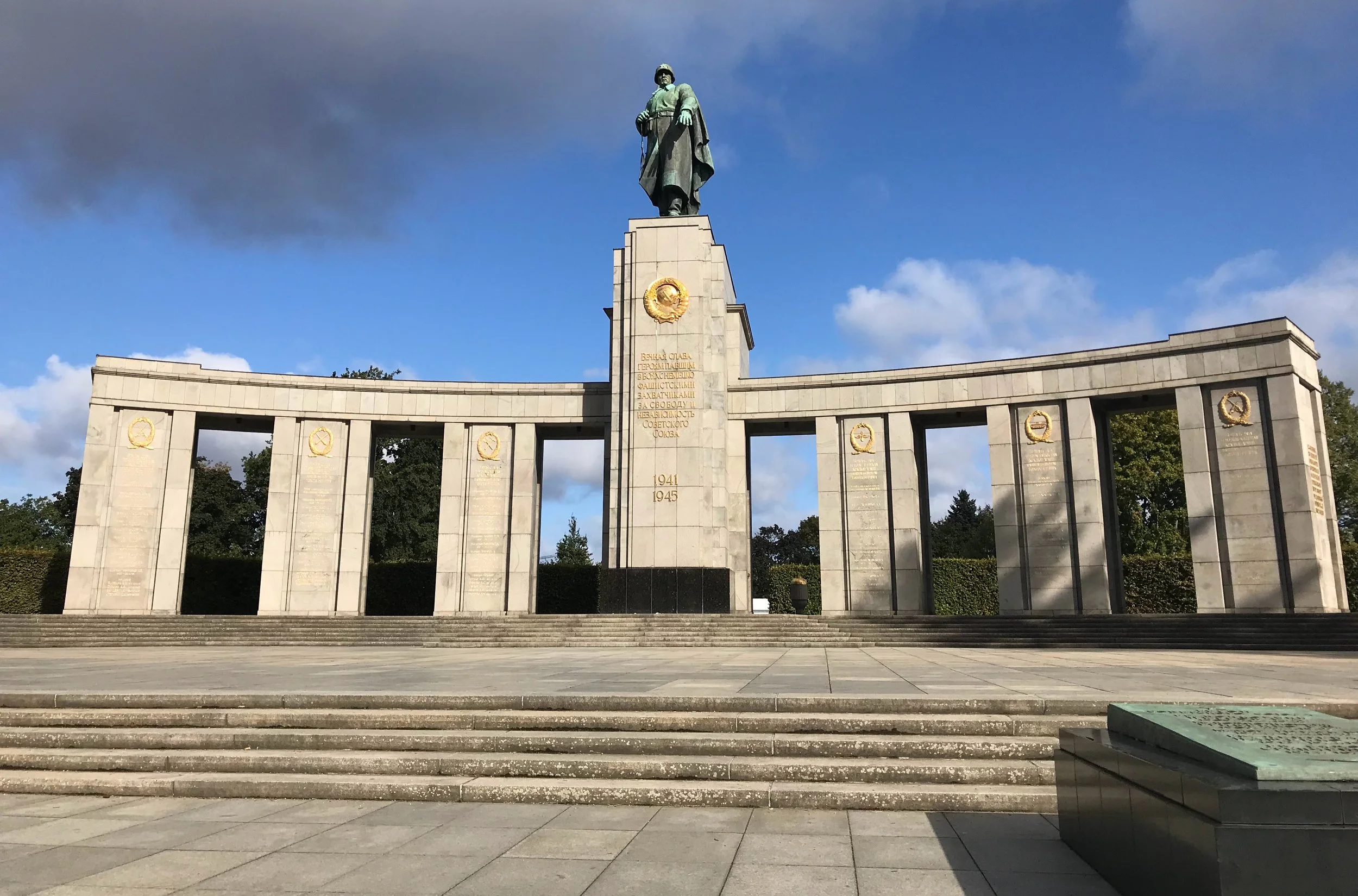 Soviet War Memorial in Berlin’s Tiergarten with red star monument, soldier statues, and surrounding greenery.