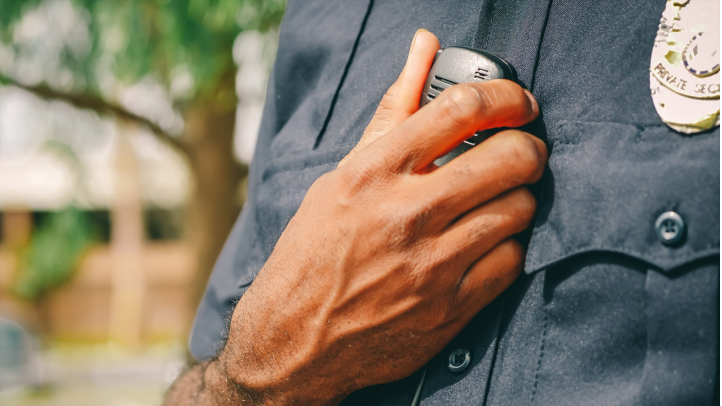 Security officer keying a radio microphone to relay a behavioral observation