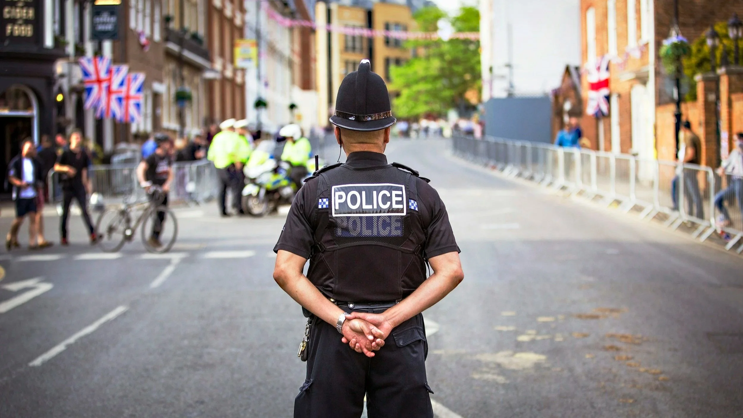Police officer calmly observing a public scene, representing structured observation as an alternative to force