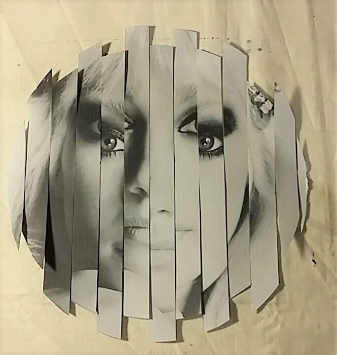 A black and white paper collage artwork of a woman's face, split into vertical strips, giving a fragmented appearance.