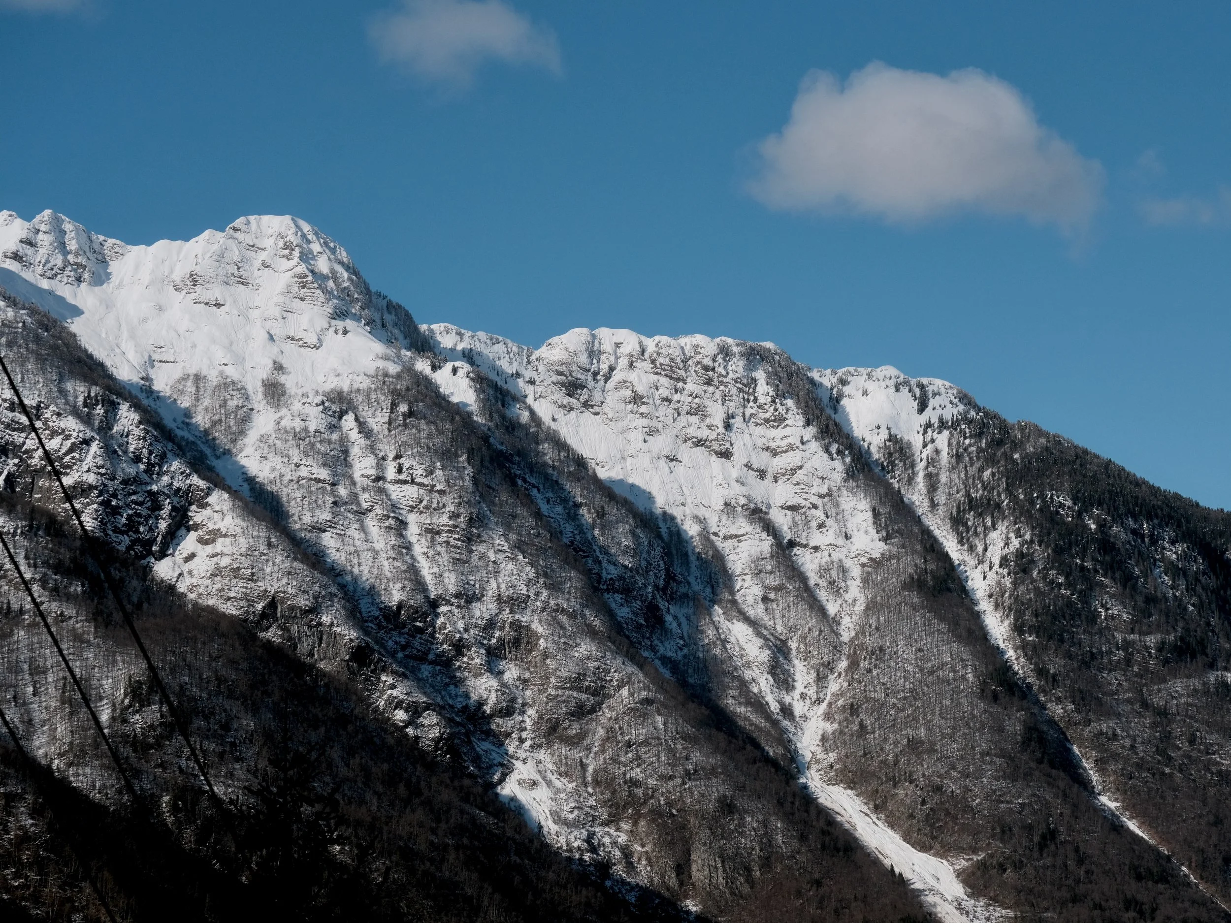 Snow-covered mountains with a blue sky and a few clouds.