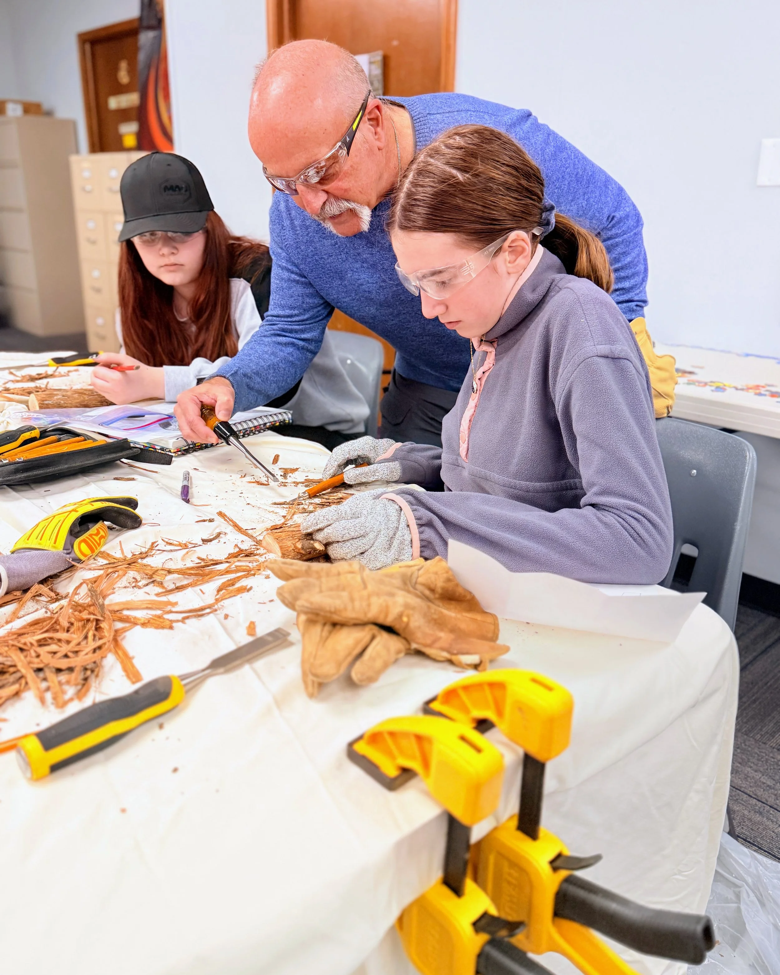 Woodworking teacher August helps his students make totems