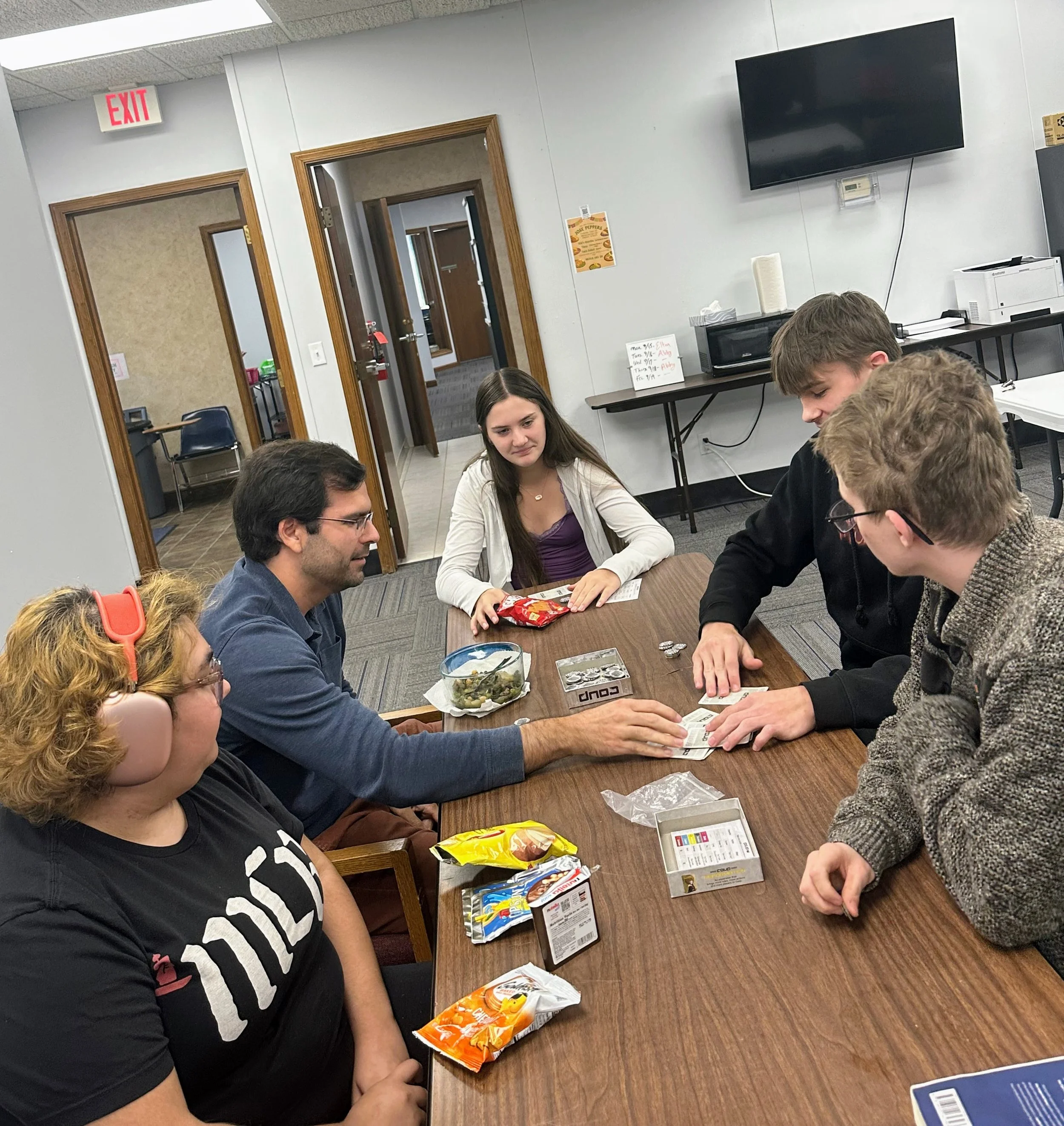 ELA teacher David plays the card game Coup with students during lunch