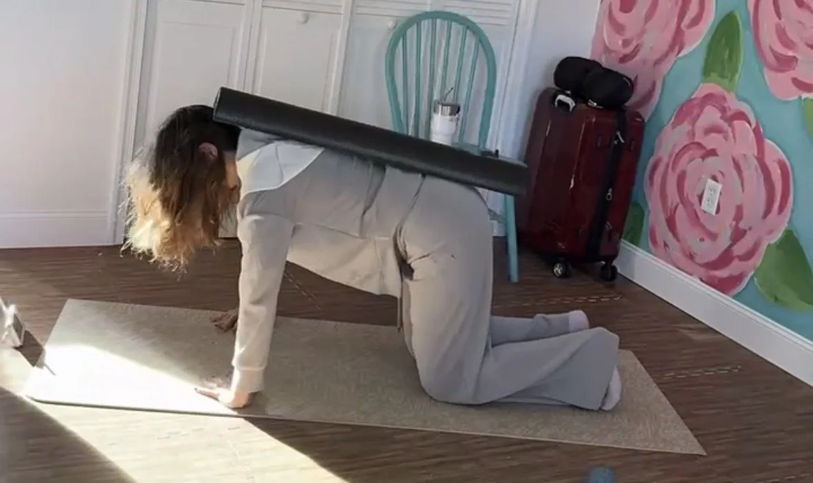 Postpartum woman performs Low Pressure Fitness pose of Gaia using a foam roller to help align posture.