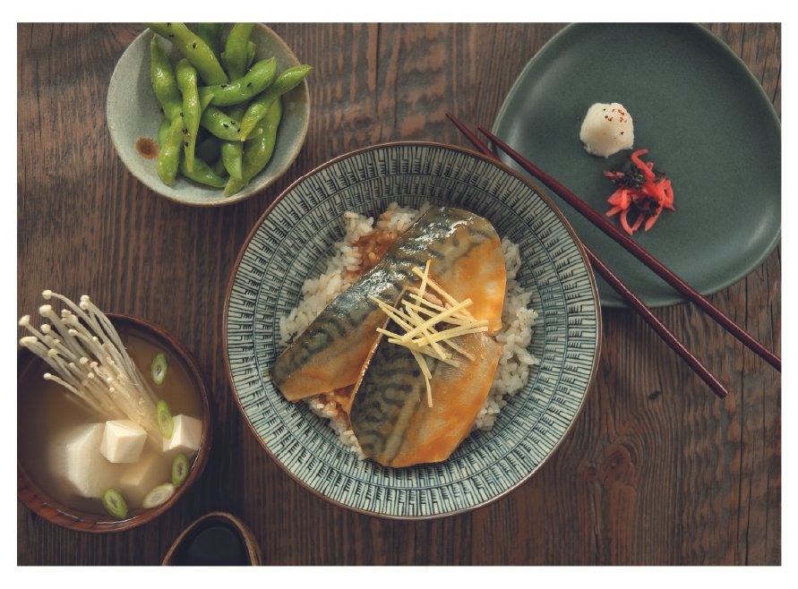 Traditional Japanese meal with grilled mackerel on rice, miso soup with tofu and mushrooms, edamame, and garnish on a plate with chopsticks.