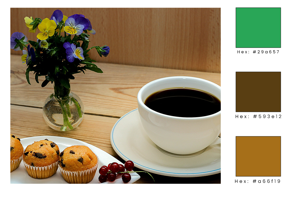 a cup of coffee in a white mug on a wooden table with flowers, muffins, and grapes near it