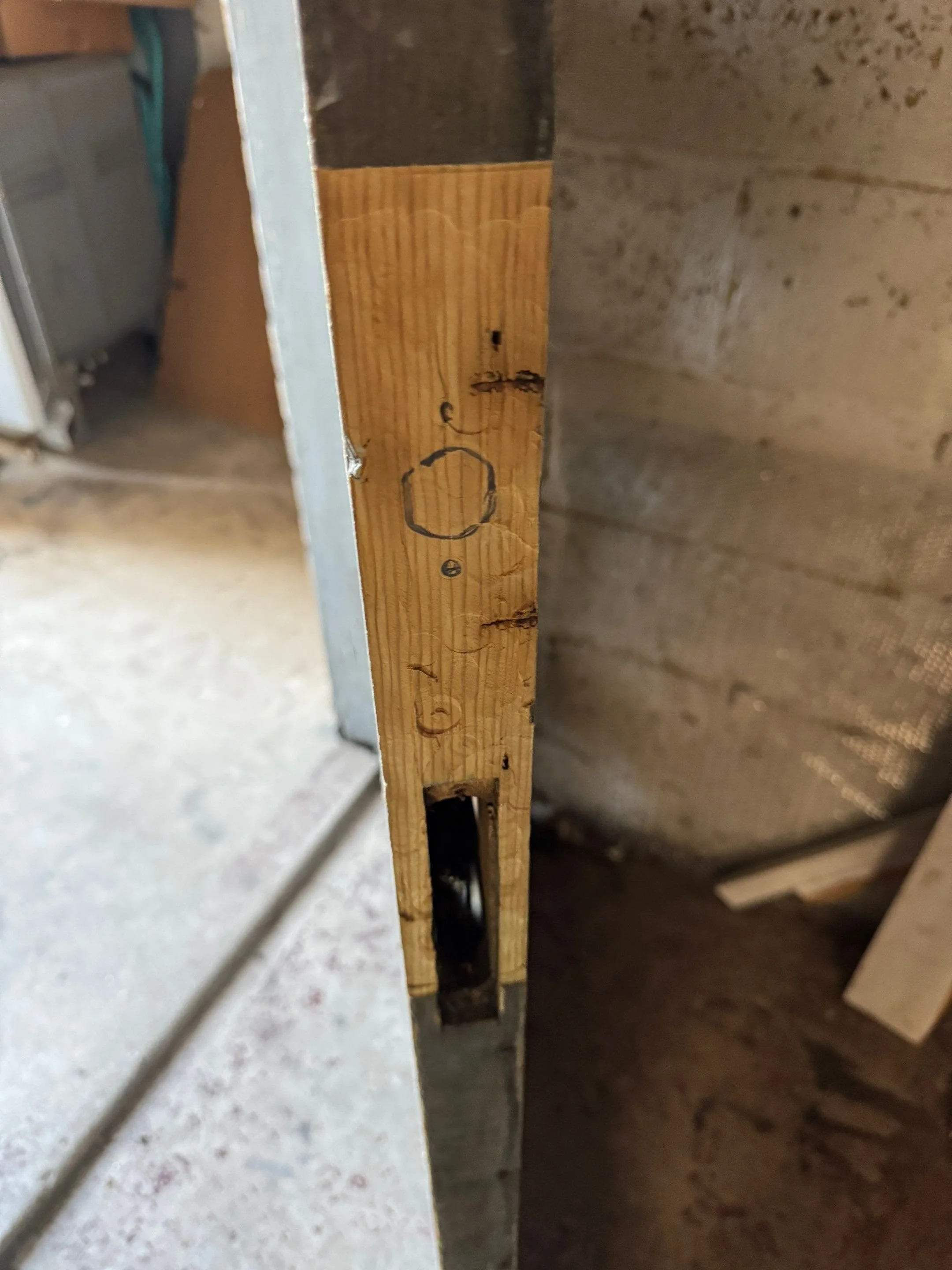 Damaged door edge showing hollow mortise cavity and splintered wood prior to repair (side view)