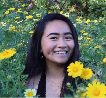 Person smiling in a field of yellow daisies.