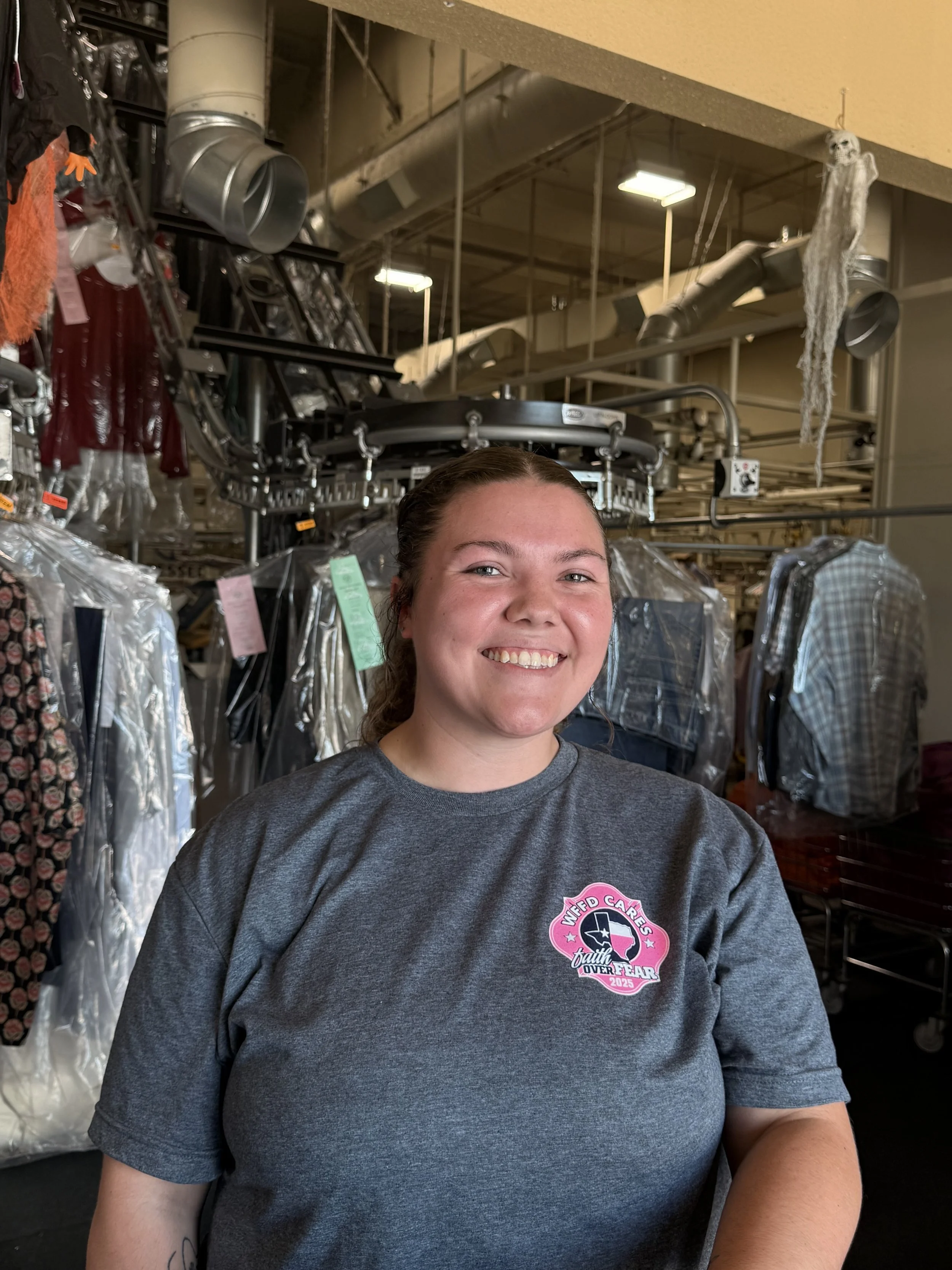 Lauren Uncel smiling at the camera, seated at a desk with a computer, at Pressed Dry Cleaners in Wichita Falls, TX.