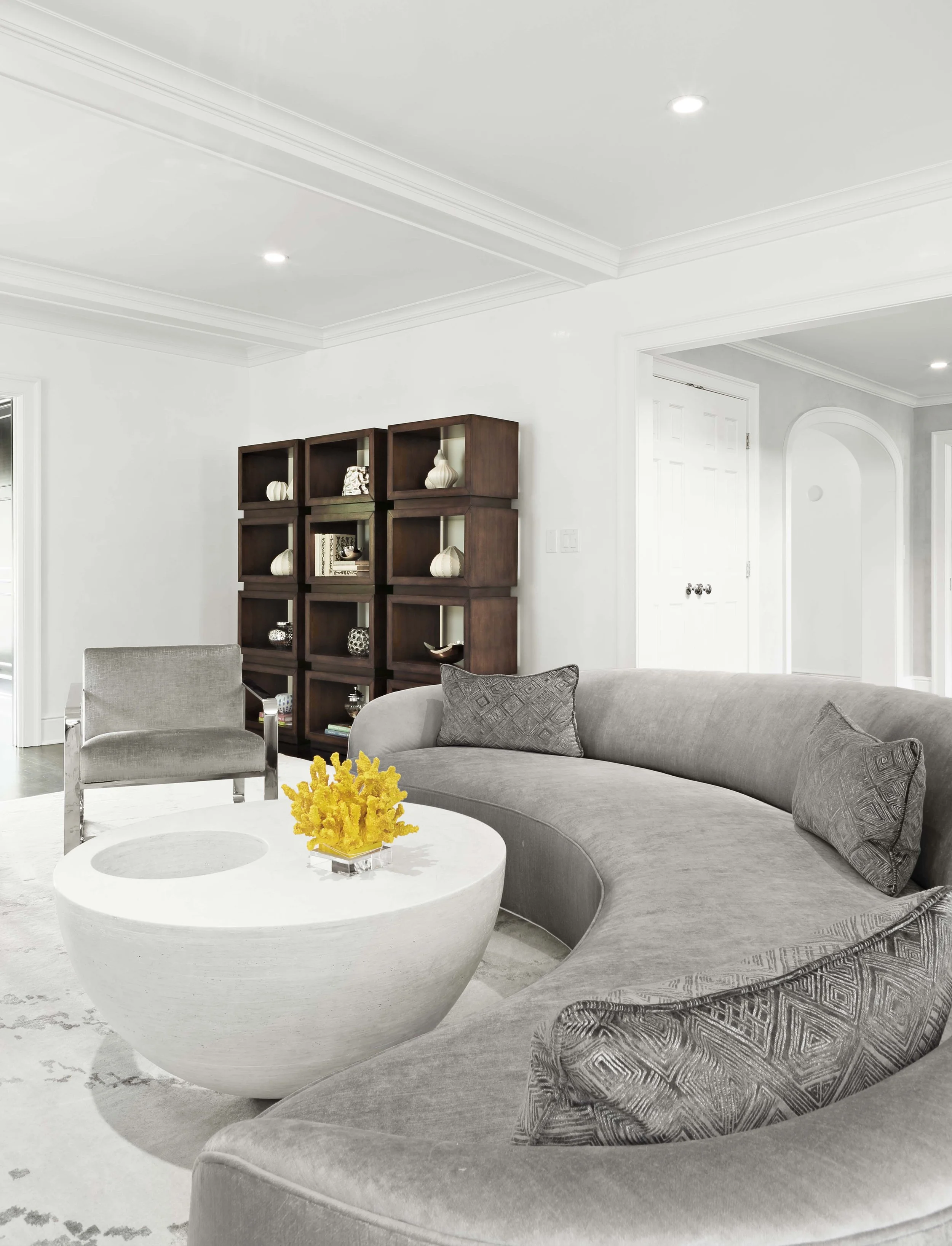 Living room seating arrangement at the Meeting House in Greenwich, CT featuring curved upholstery and custom shelving created by Luminosus Designs.
