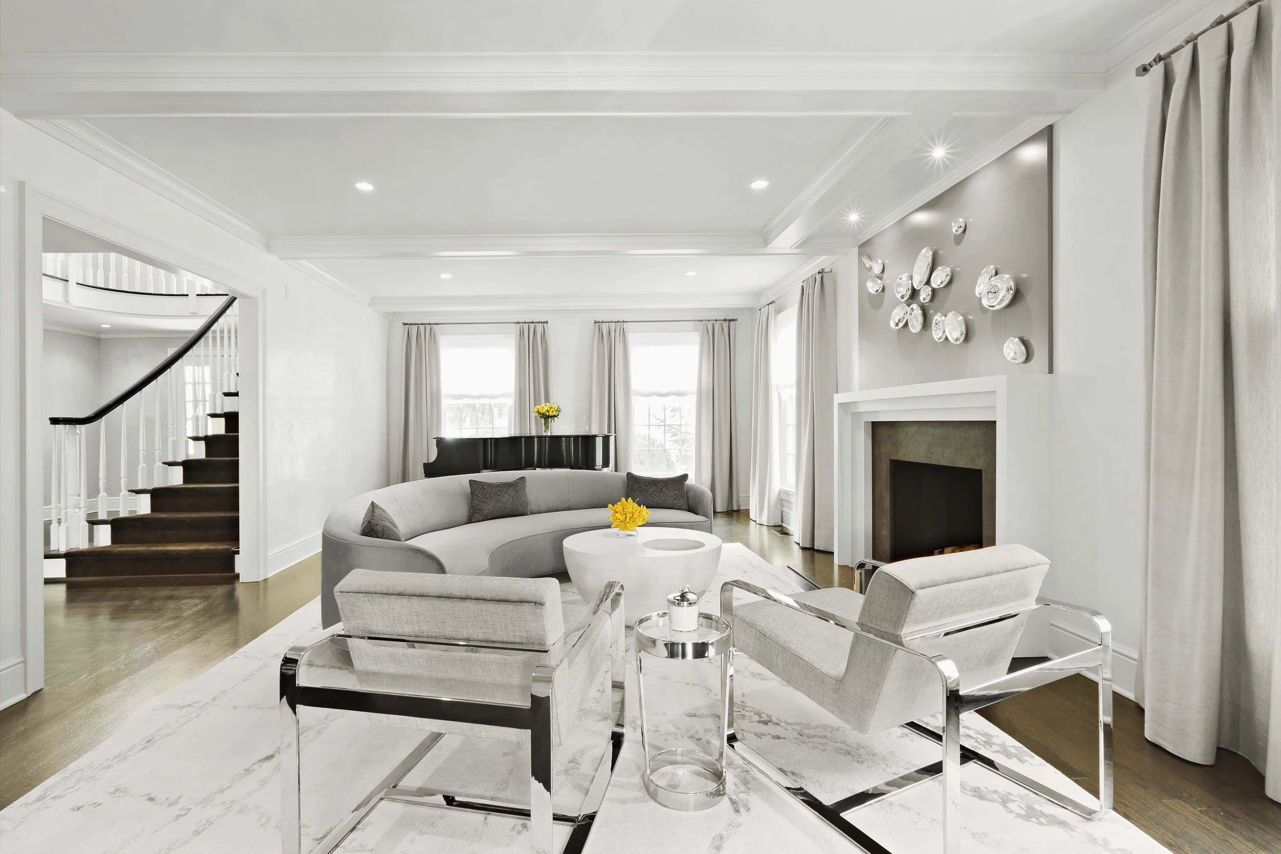 Wide view of the living room at the Meeting House in Greenwich, CT showcasing a curved sofa, sculptural coffee table, and fireplace.