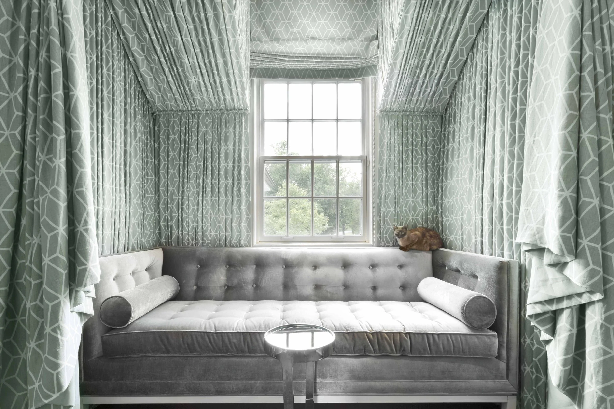 Reading nook at the Meeting House in Greenwich, CT featuring a custom upholstered window seat framed by patterned drapery.
