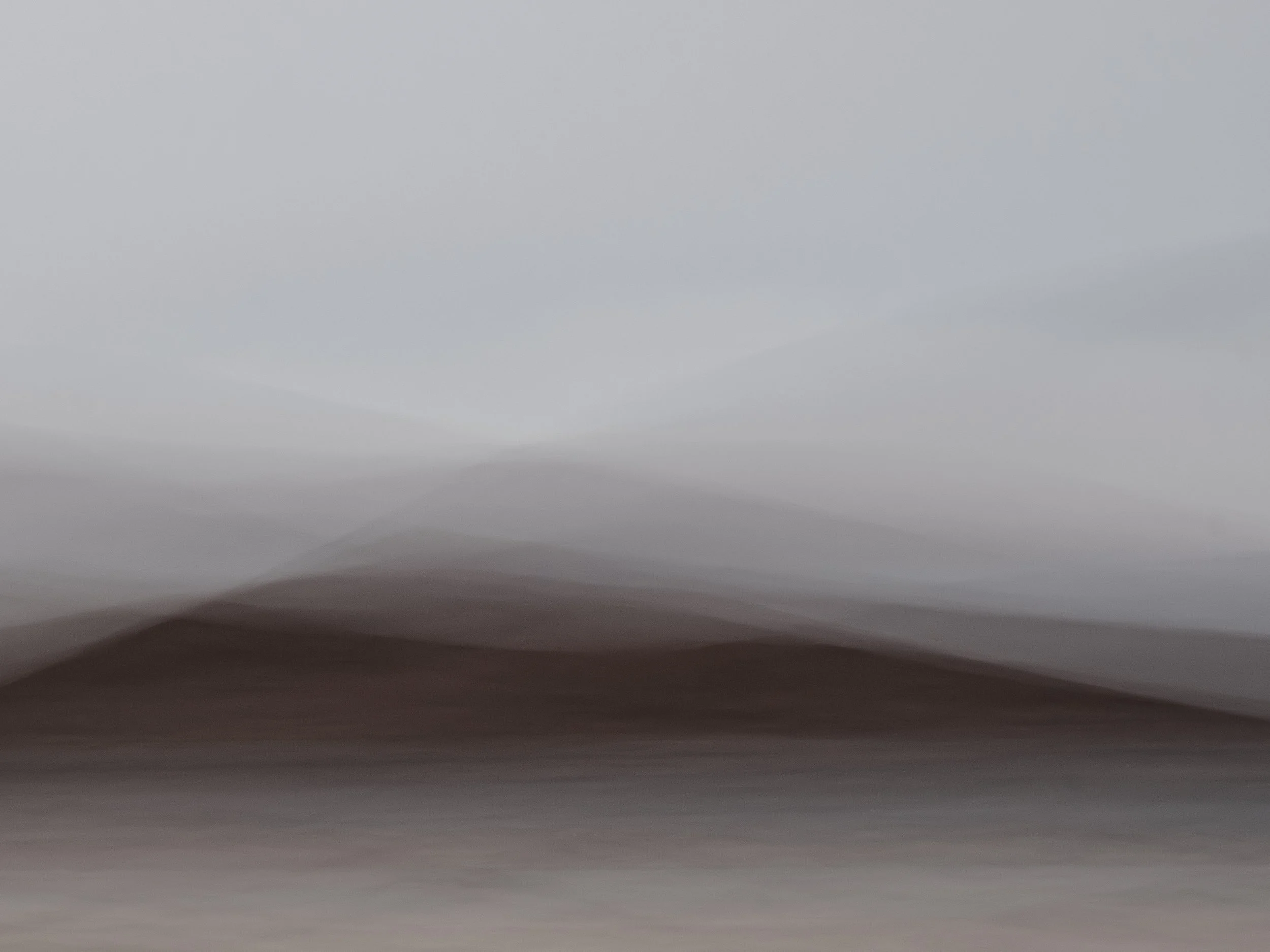 A minimalist fine art landscape created using Intentional Camera Movement (ICM), featuring misty, layered hills in muted earth tones. The gentle motion and soft gradients create an ethereal, dreamlike atmosphere, evoking a sense of silence and stilln