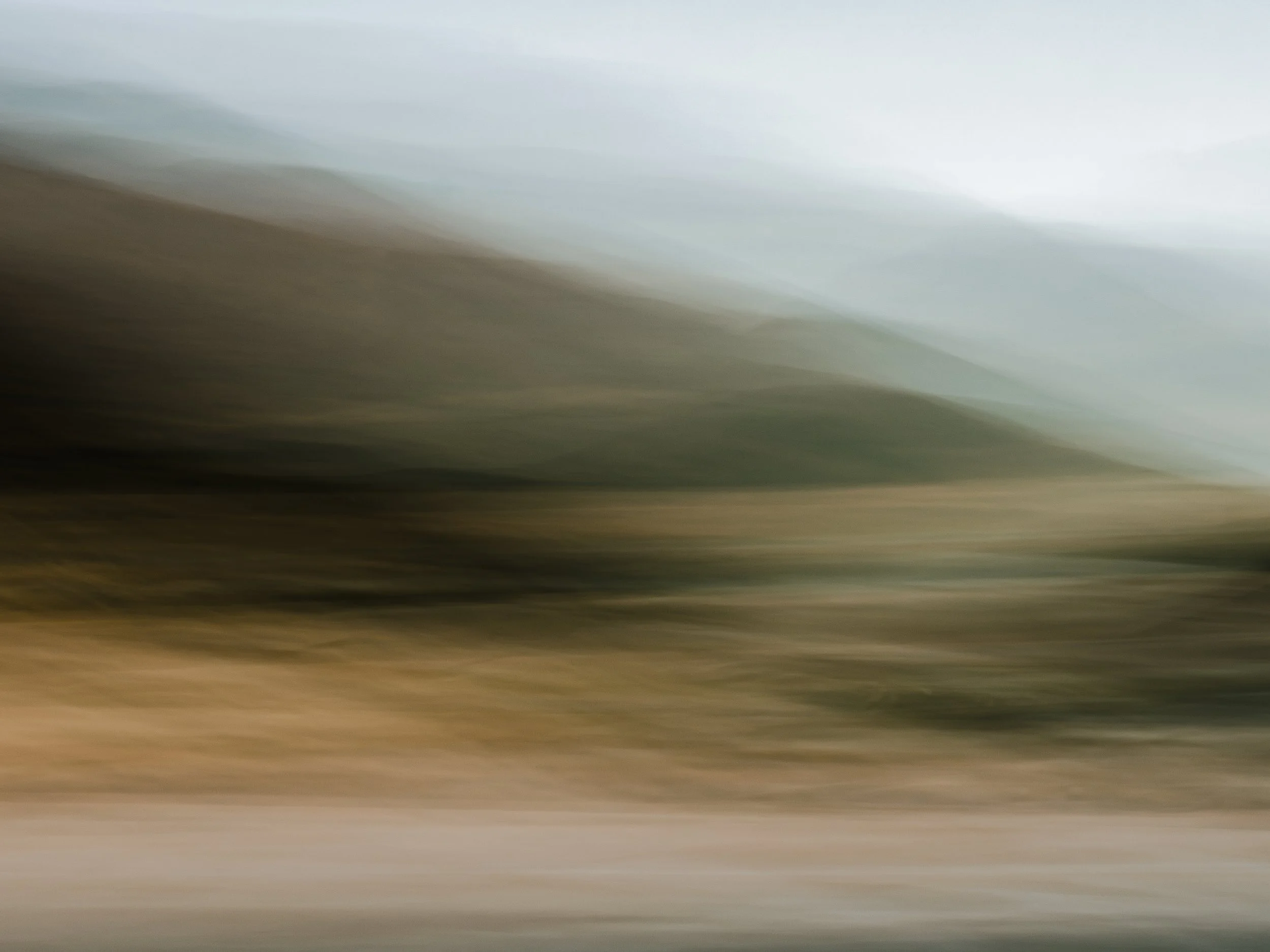 A captivating fine art landscape created using Intentional Camera Movement (ICM), featuring rolling green and earthy brown hills that dissolve into misty blue tones. The painterly motion and soft layering create a dreamlike, immersive atmosphere, mak