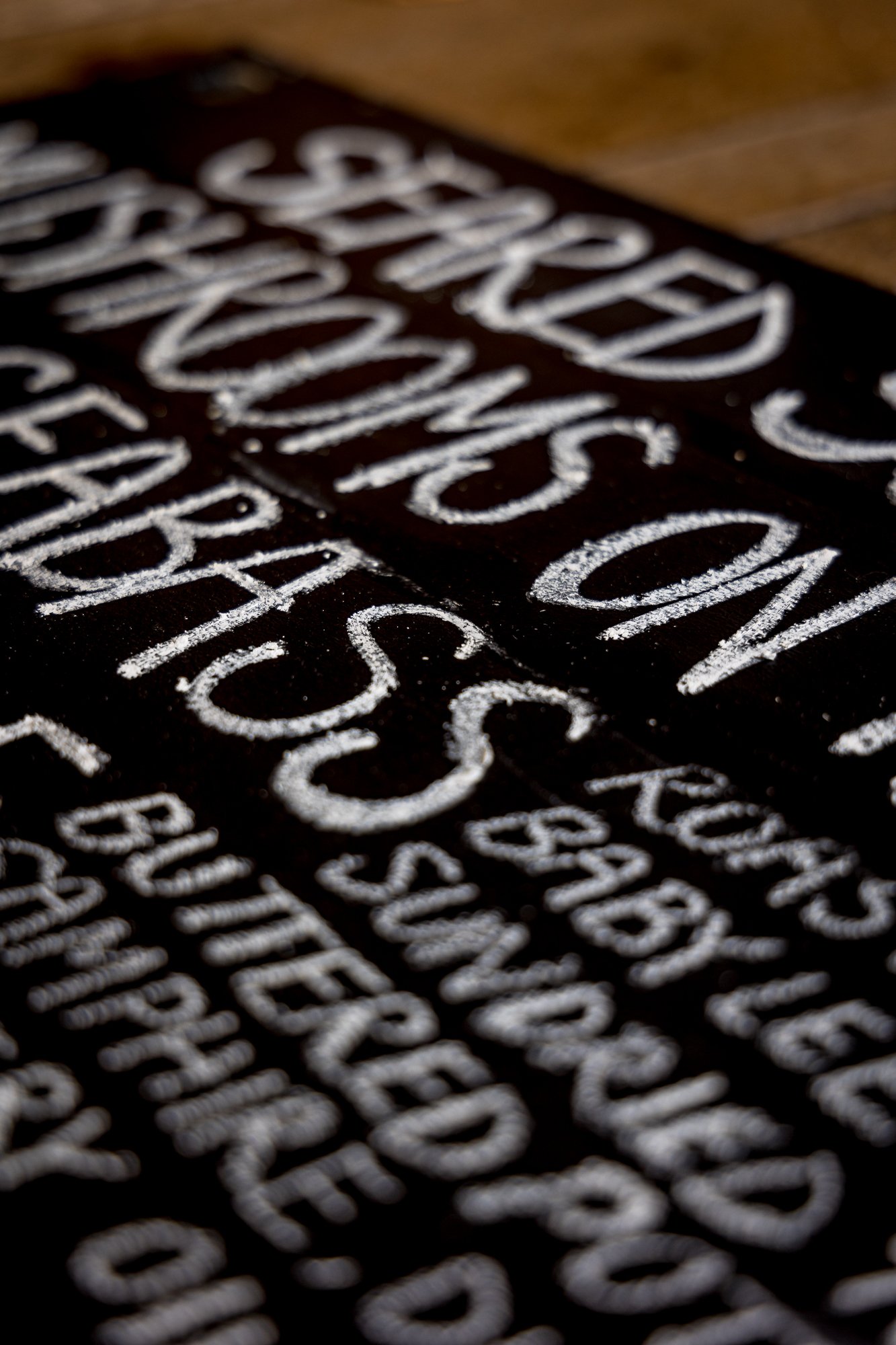 Close-up of a black chalkboard with handwritten white text listing various menu items.